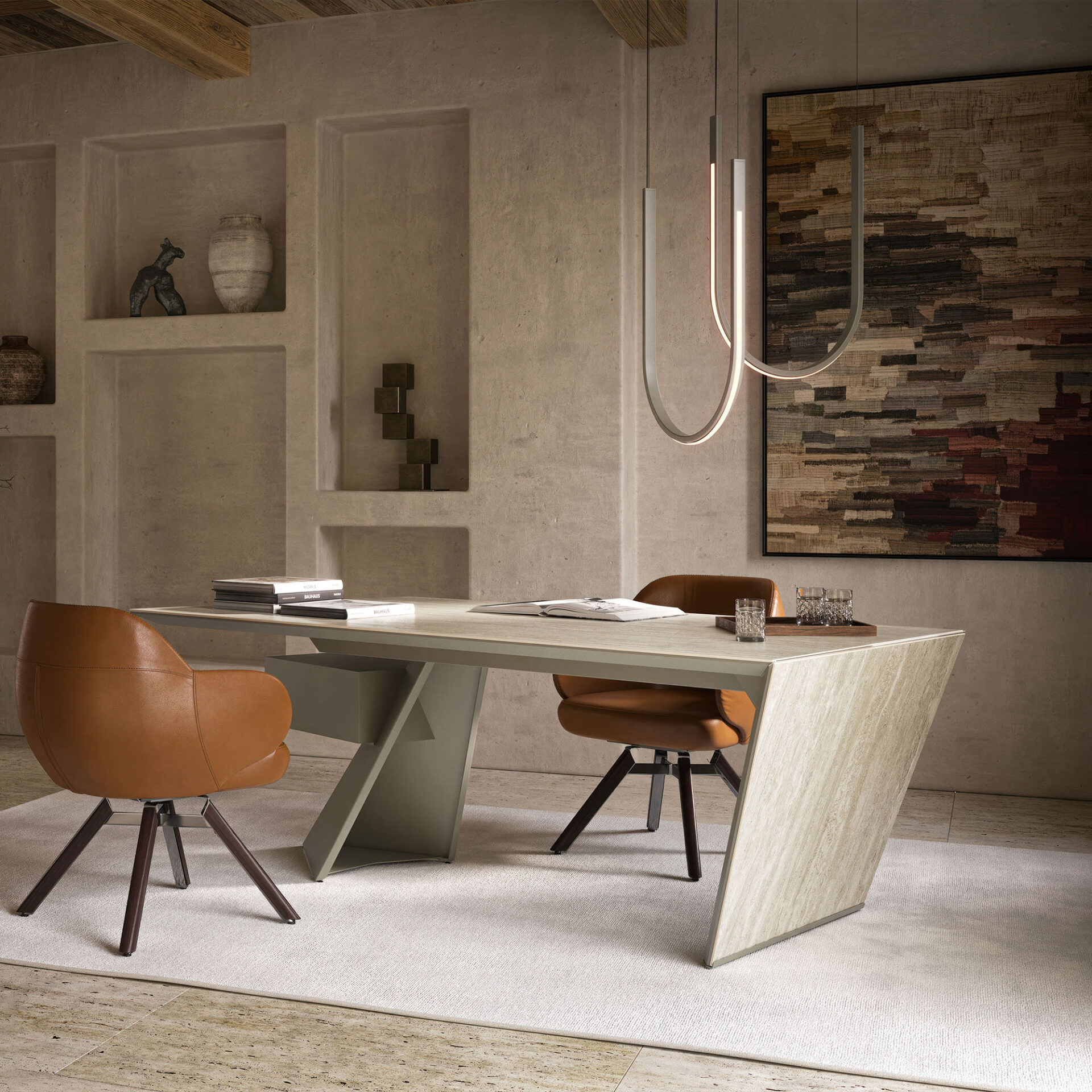 A modern home office with a large light-colored stone desk, two brown leather chairs, textured greige walls with decorative niches, and a contemporary U-shaped chandelier. An abstract artwork hangs on the right wall, and a light rug covers part of the stone floor.