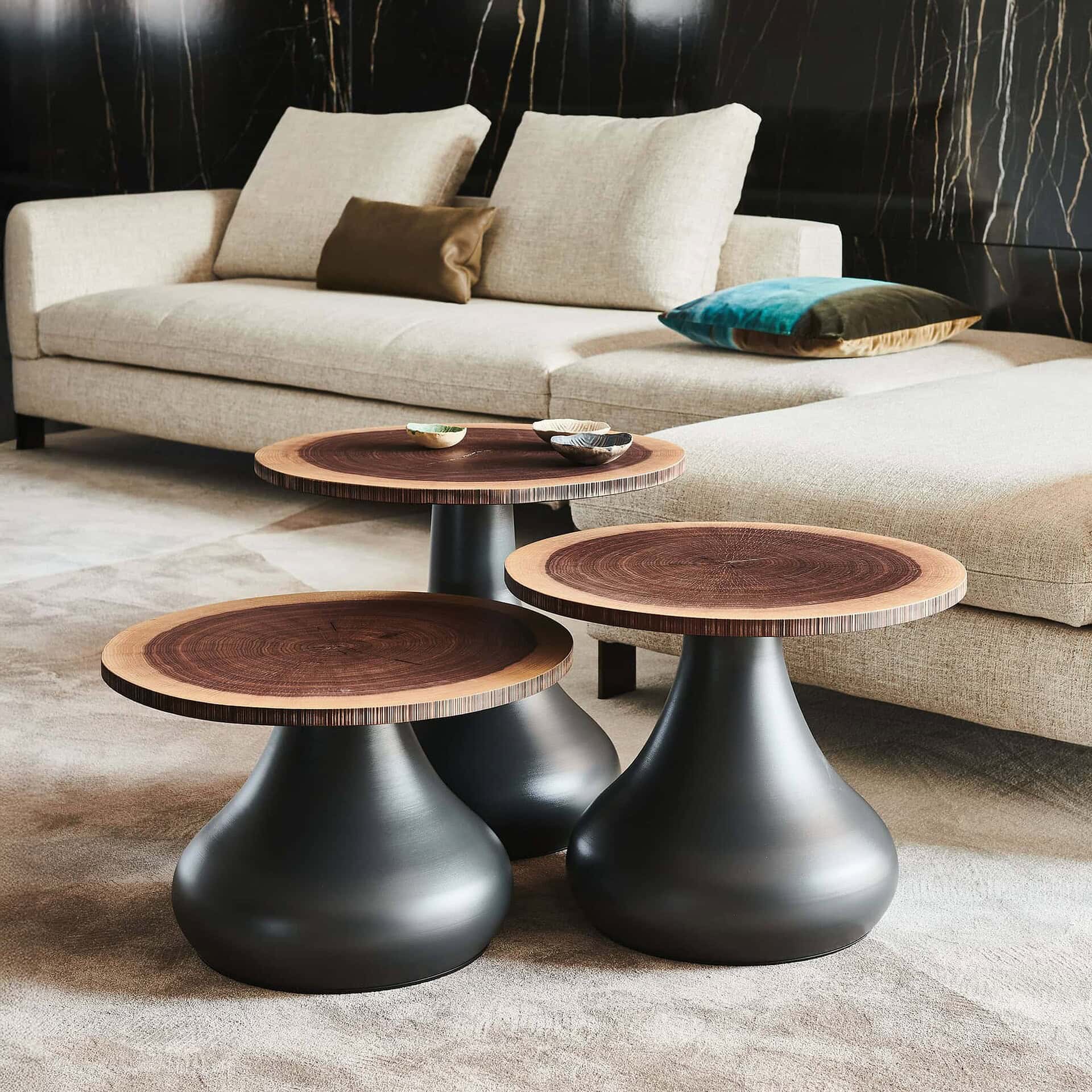 Set of Rio coffee tables with natural walnut log tops and sculptural black bases placed in a modern living room.