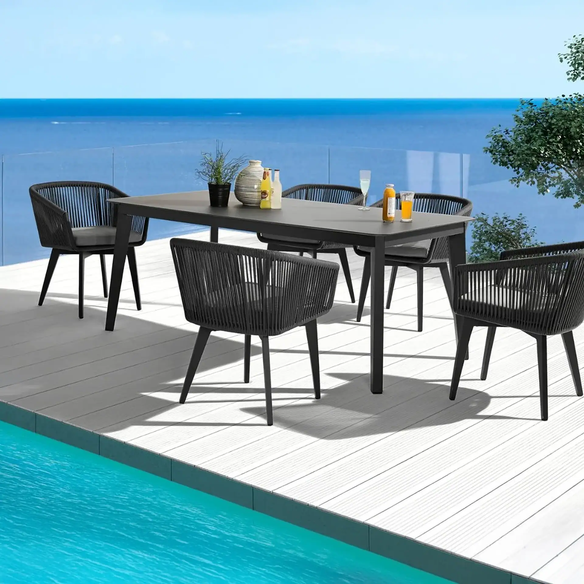 Outdoor dining table with black chairs overlooking the ocean.