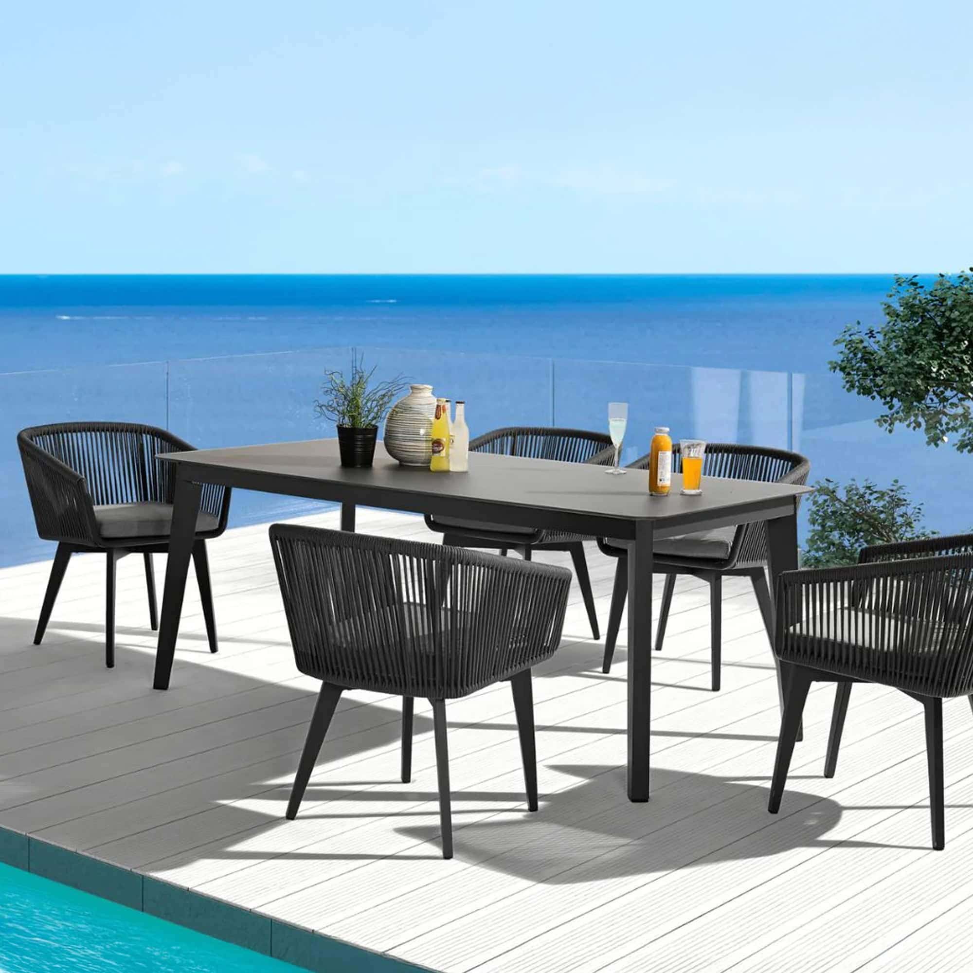 Outdoor dining table with black chairs overlooking the ocean.