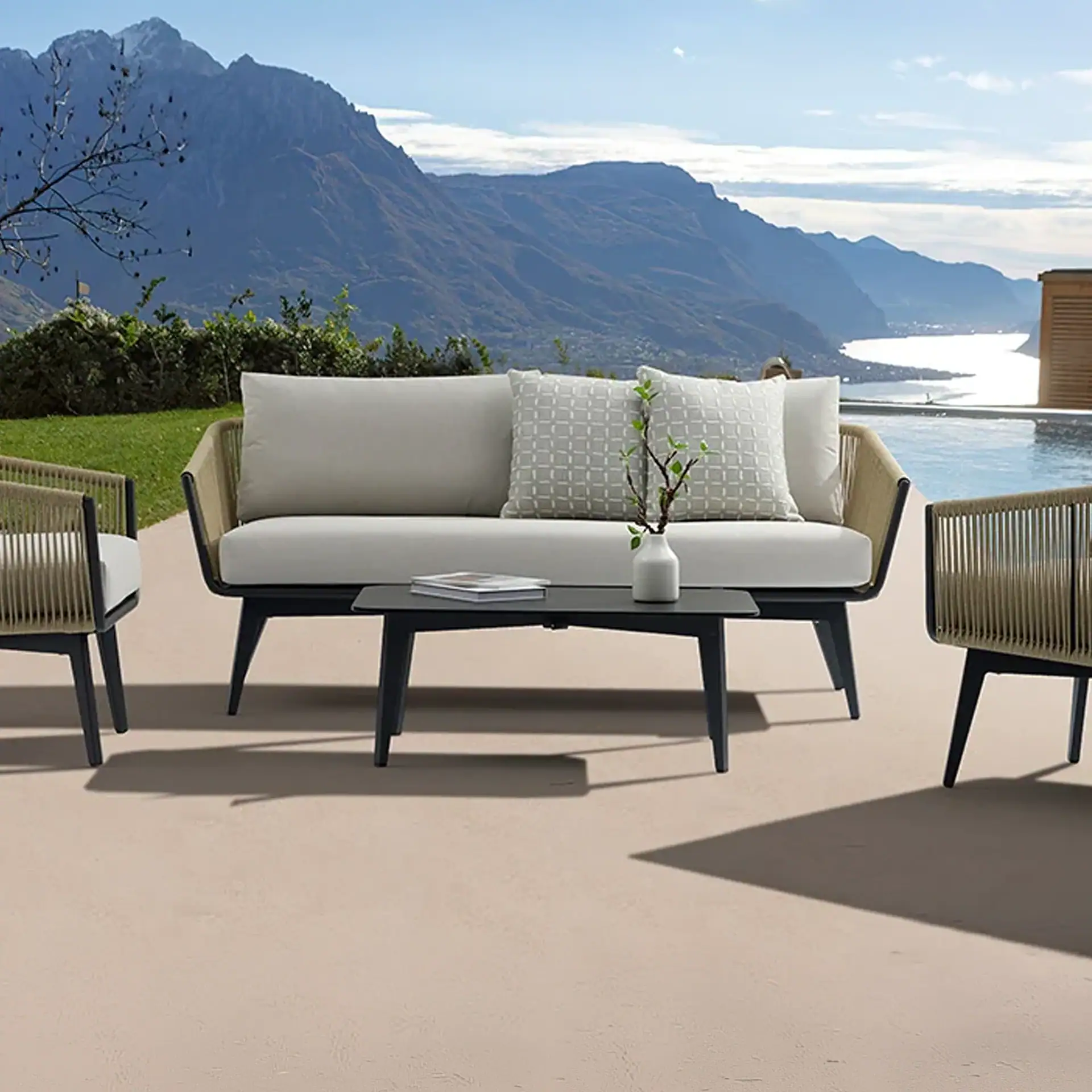 Outdoor patio furniture set with a sofa, two chairs, and a coffee table, overlooking a mountain and lake landscape.