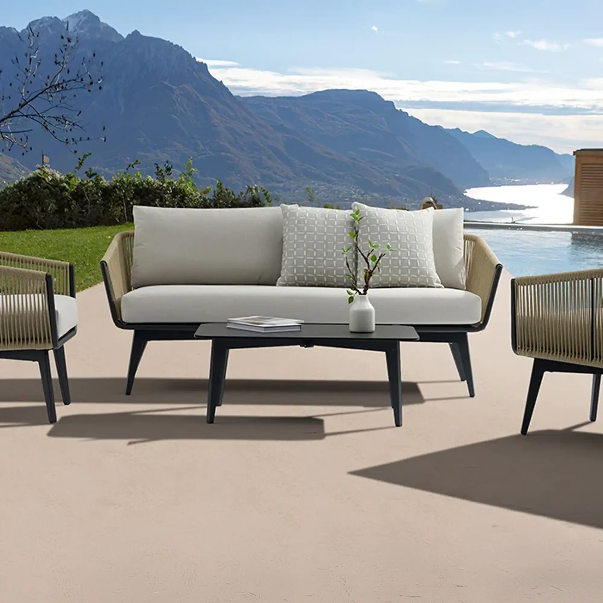 Outdoor patio furniture set with a sofa, two chairs, and a coffee table, overlooking a mountain and lake landscape.