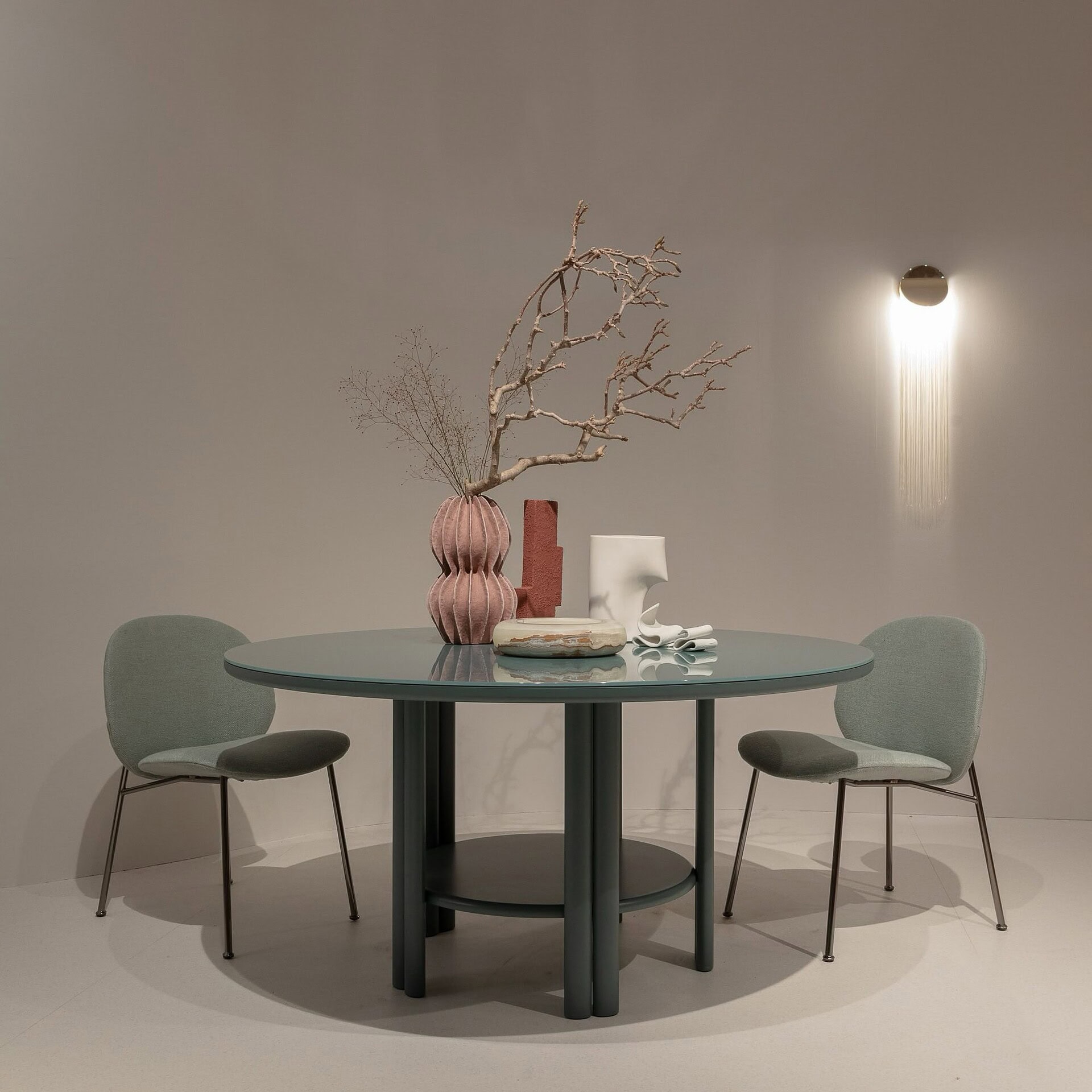 Elegant round dining table with modern chairs, minimalist décor, and stylish vases in contemporary interior design.