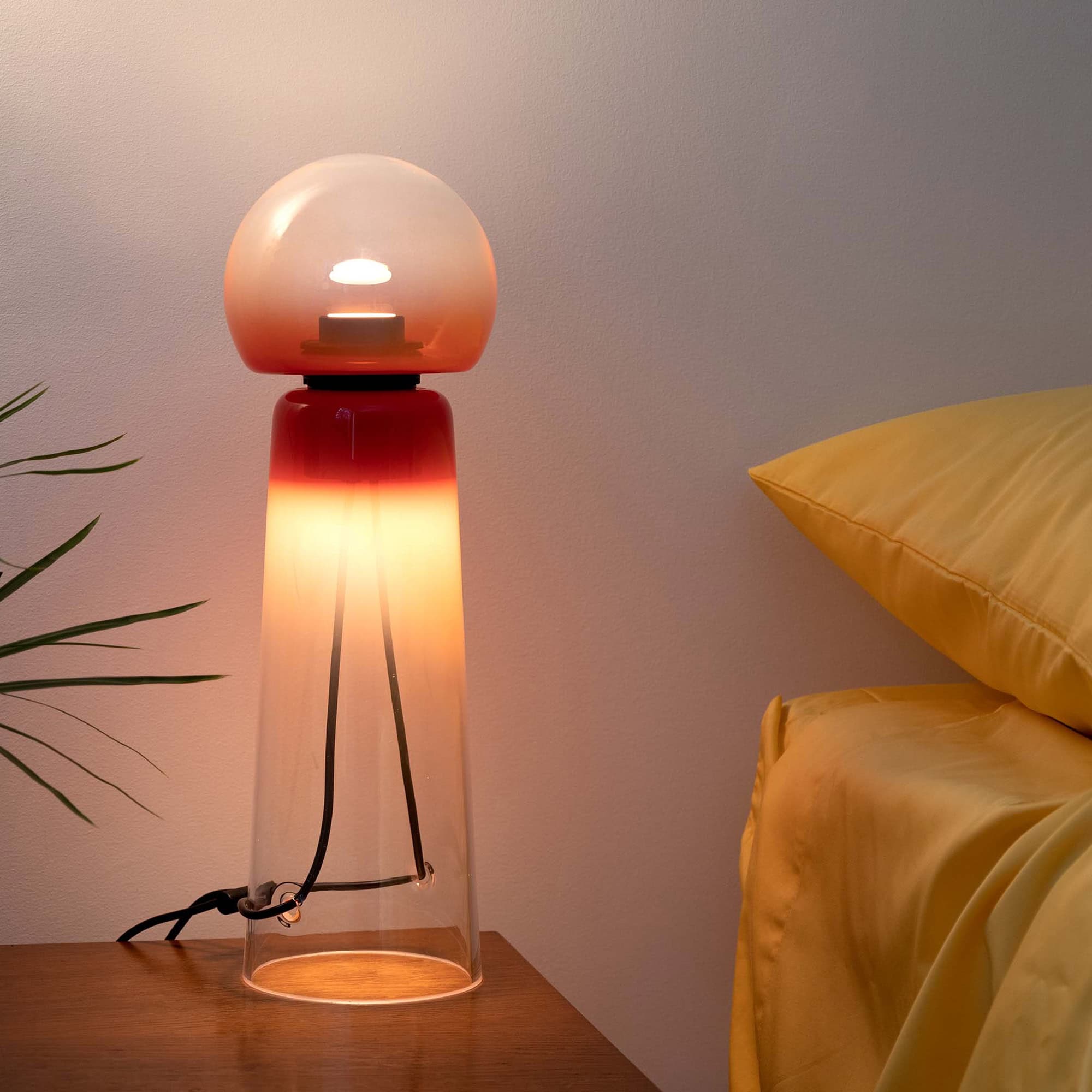 Modern designer glass table lamp with warm ambient lighting for bedroom decor.