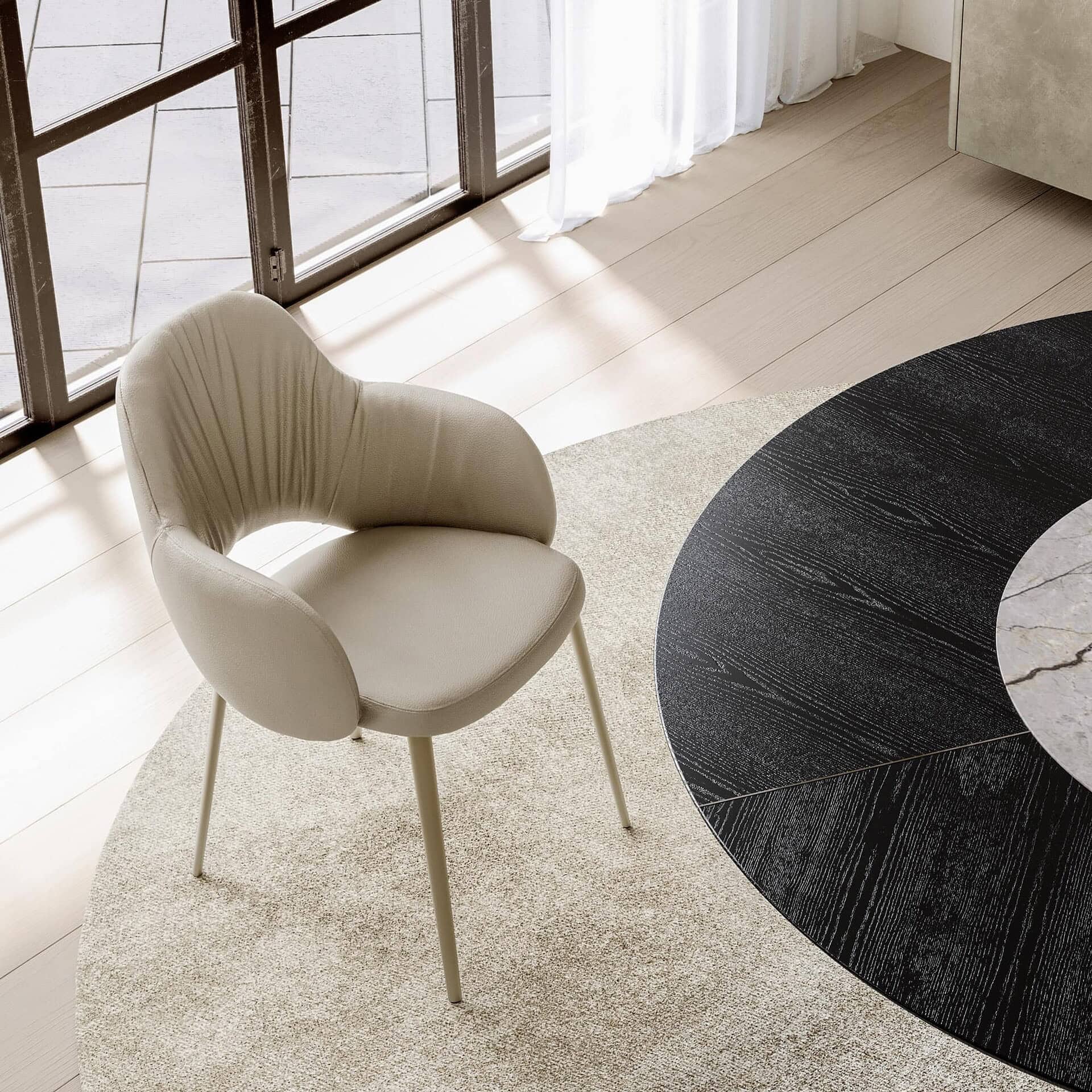 Beige Silhouette Deluxe Upholstered Armchair with gold legs, shown at an angle on a round rug in a light-filled room.