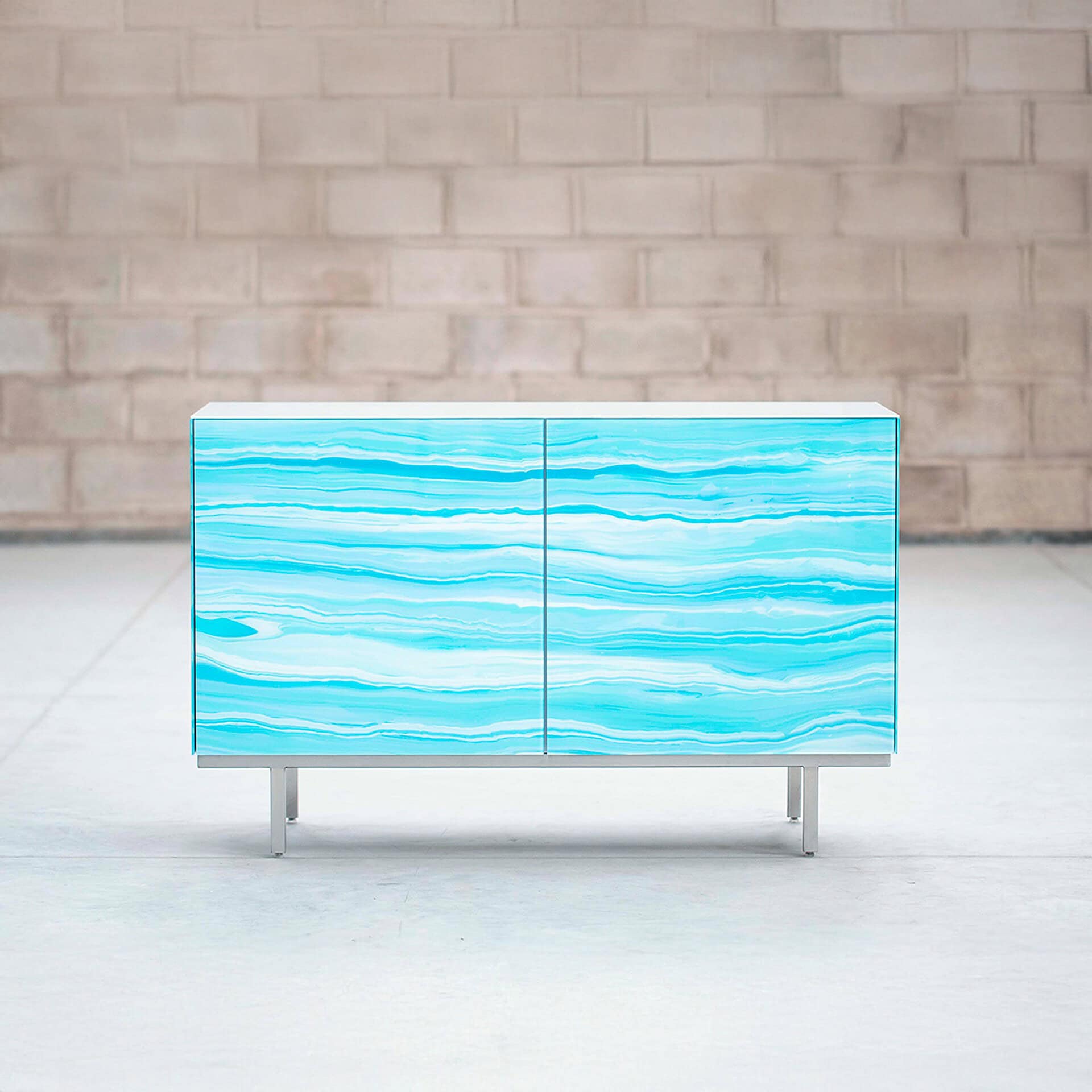 Nico 2 Door Cabinet in bright turquoise glass finish styled outdoors.