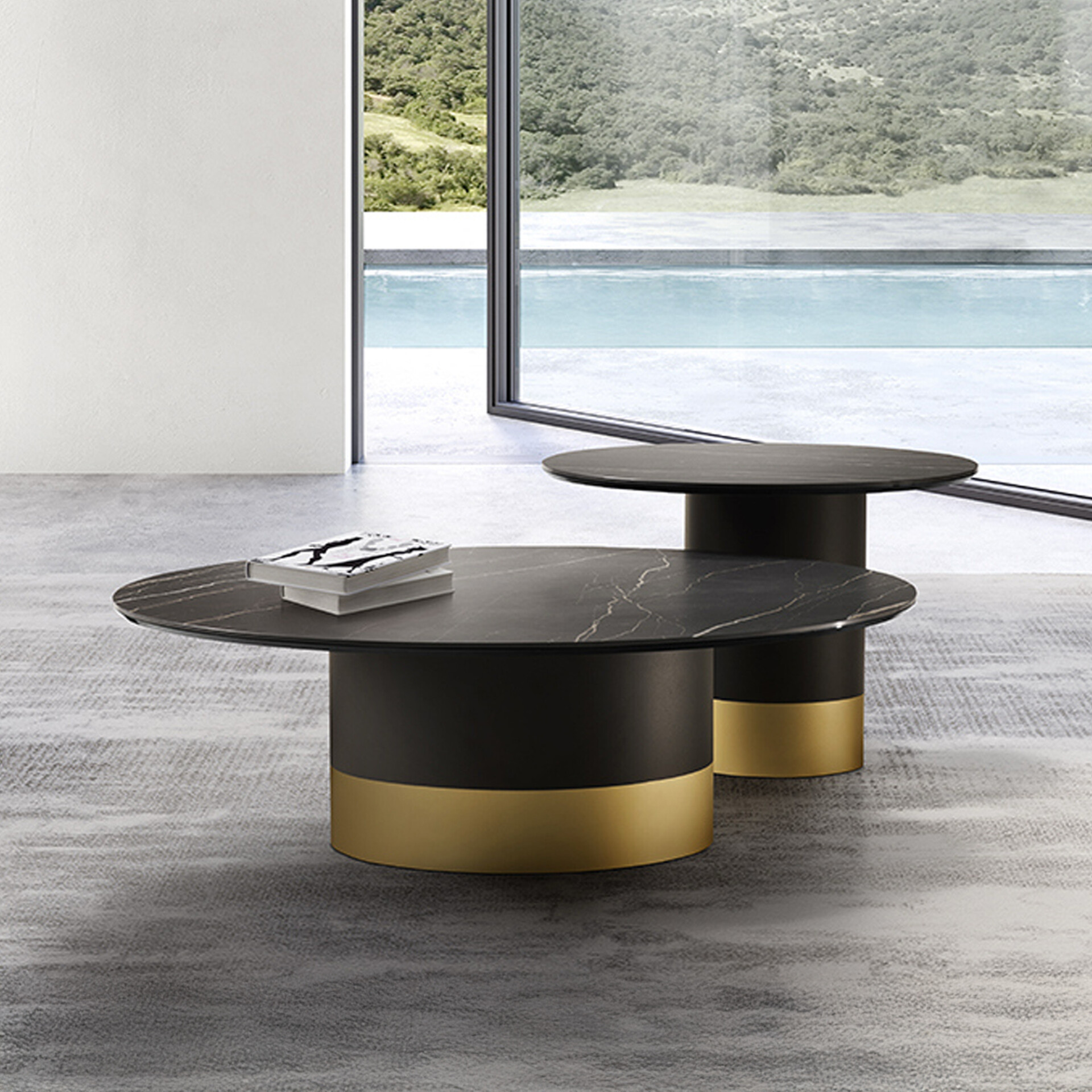 Two modern round coffee tables with black marble tops and gold-banded bases, set on a grey rug in front of a large window overlooking a swimming pool and green landscape.