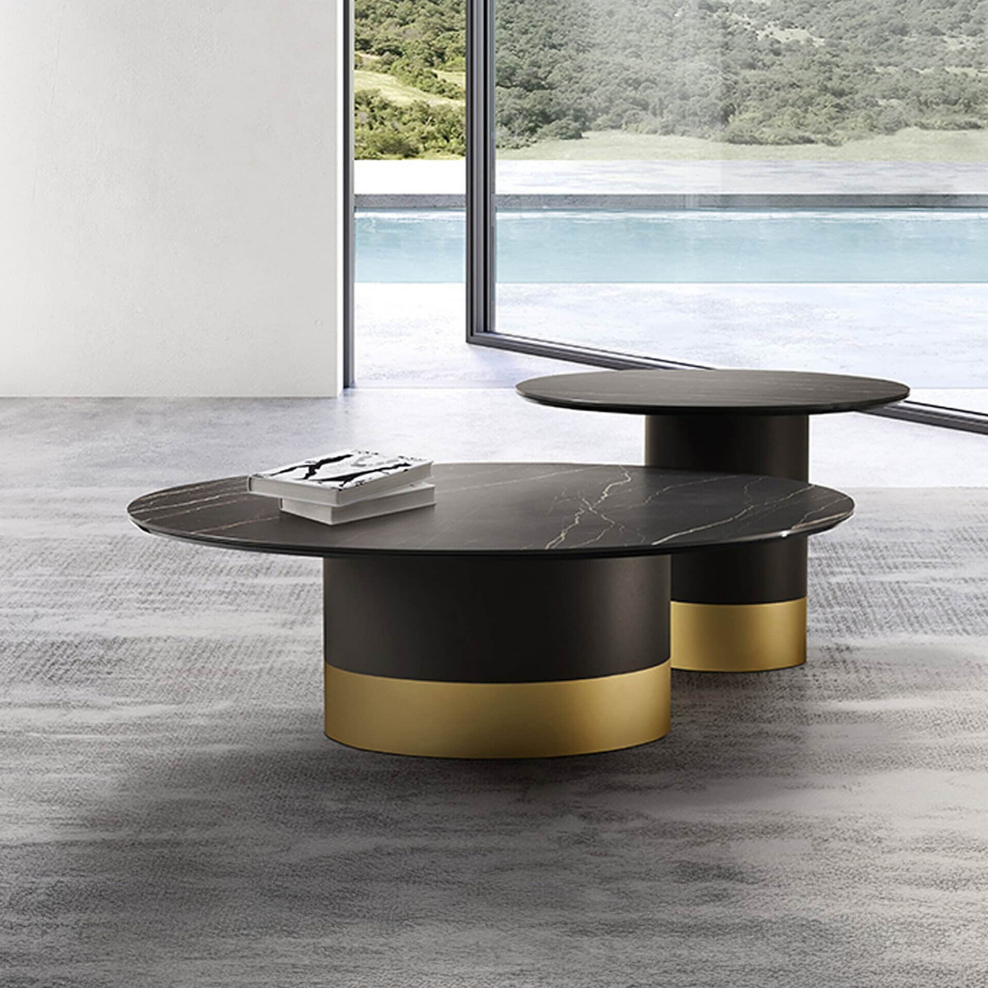 Two modern round coffee tables with black marble tops and gold-banded bases, set on a grey rug in front of a large window overlooking a swimming pool and green landscape.