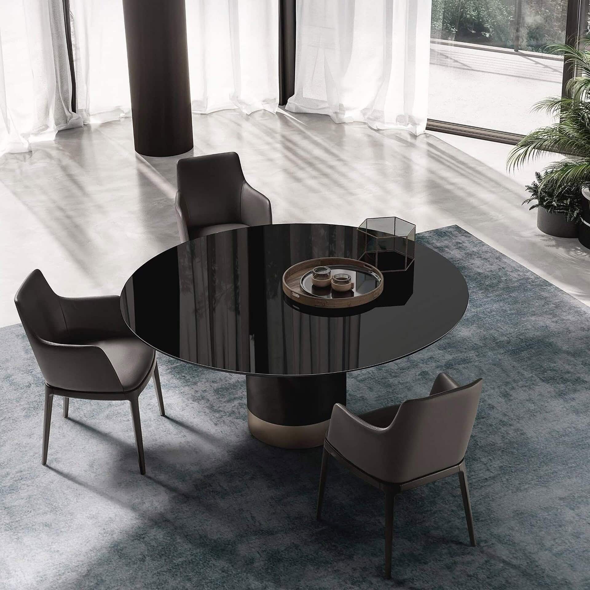 Contemporary round dining table with unique sculptural black pedestal base and modern chairs.