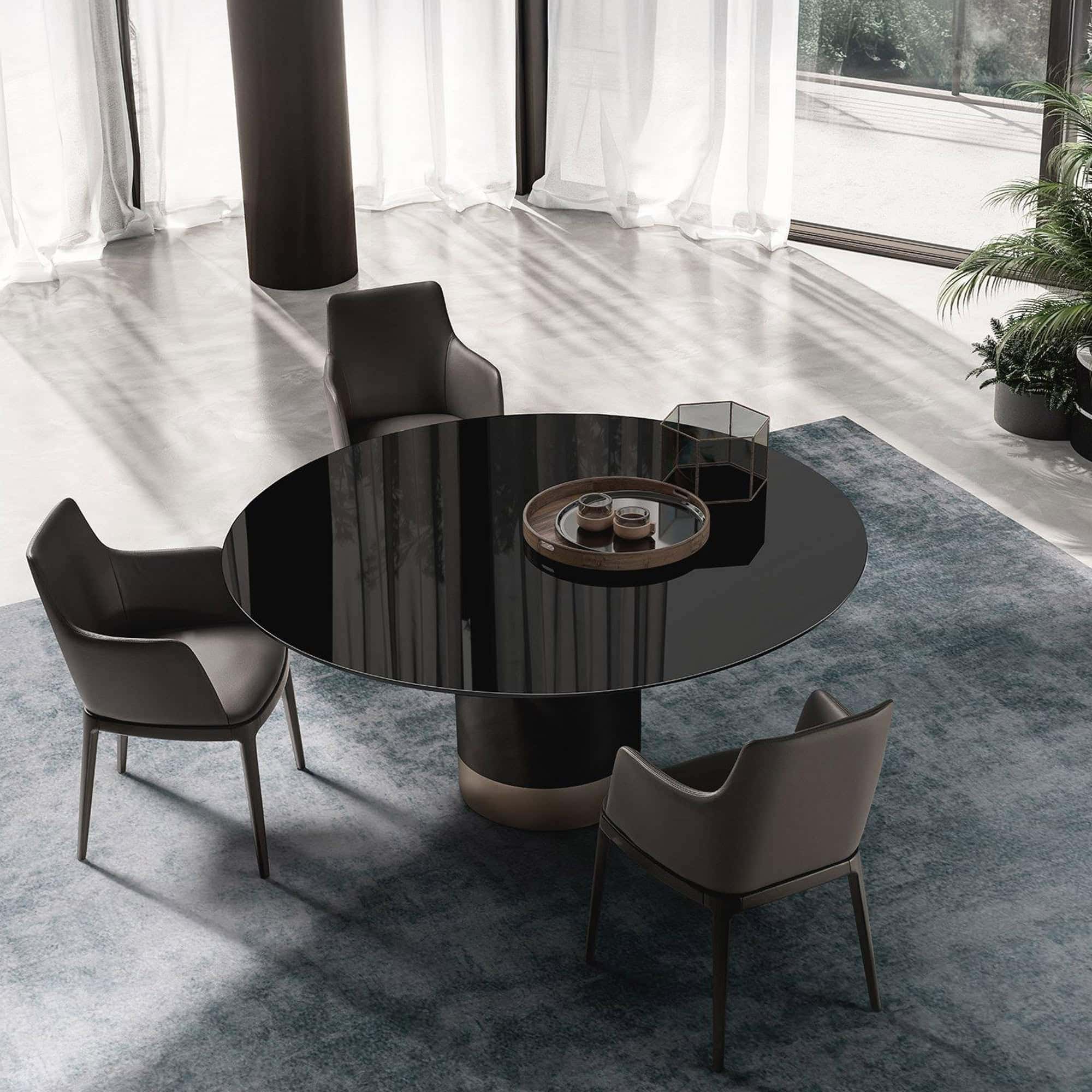 Contemporary round dining table with unique sculptural black pedestal base and modern chairs.