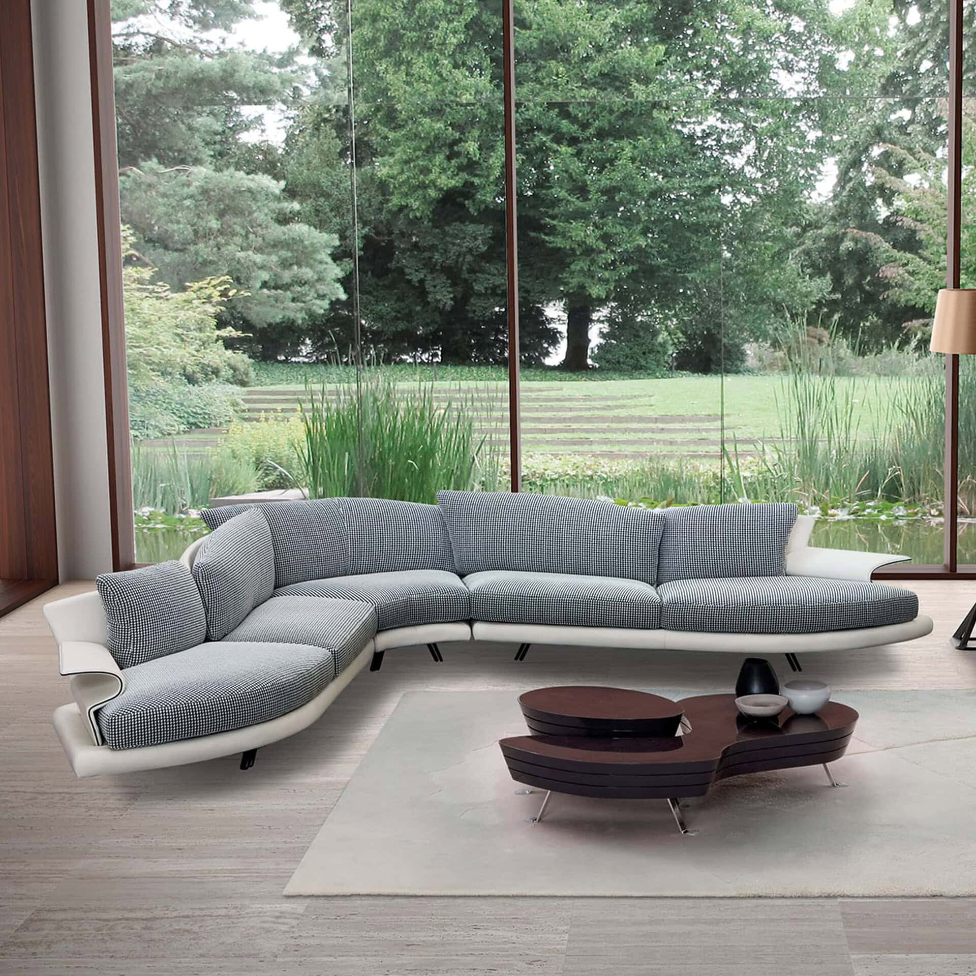 Curved sectional sofa with sculptural cushions viewed from above, styled on a round rug with a modern coffee table.