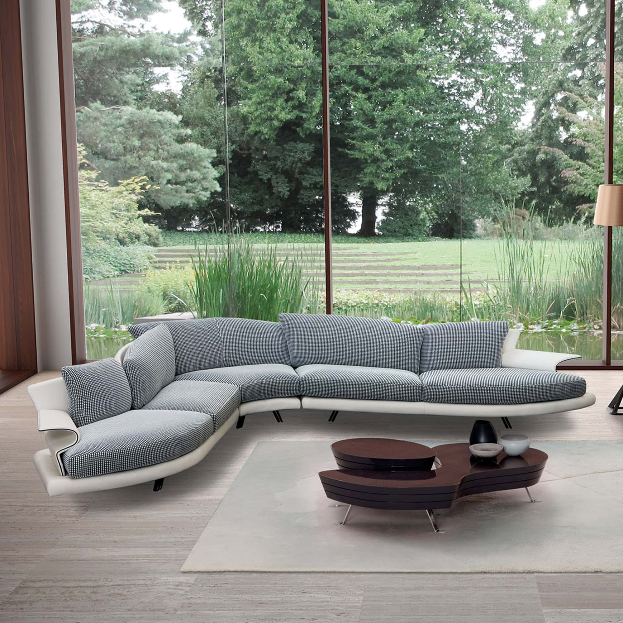 Curved sectional sofa with sculptural cushions viewed from above, styled on a round rug with a modern coffee table.