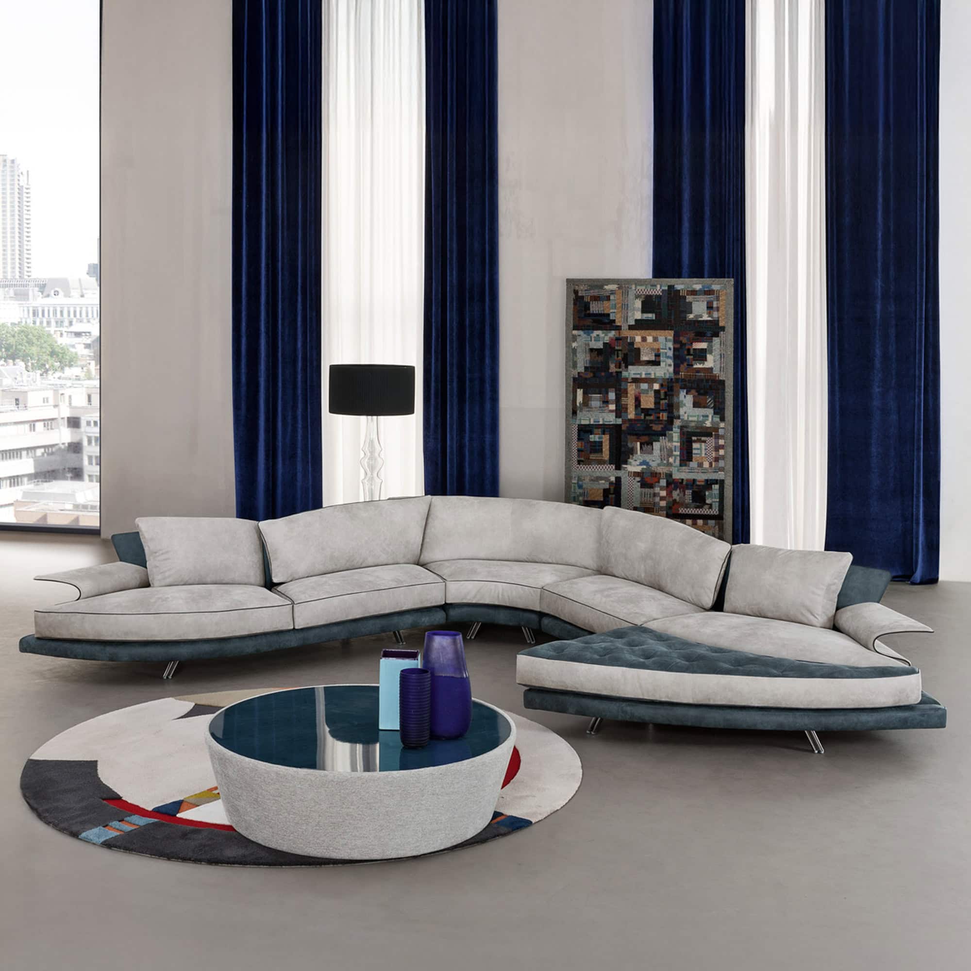 Large modular Super Roy sofa in a light finish arranged in a flowing configuration with round wooden coffee table and rug.