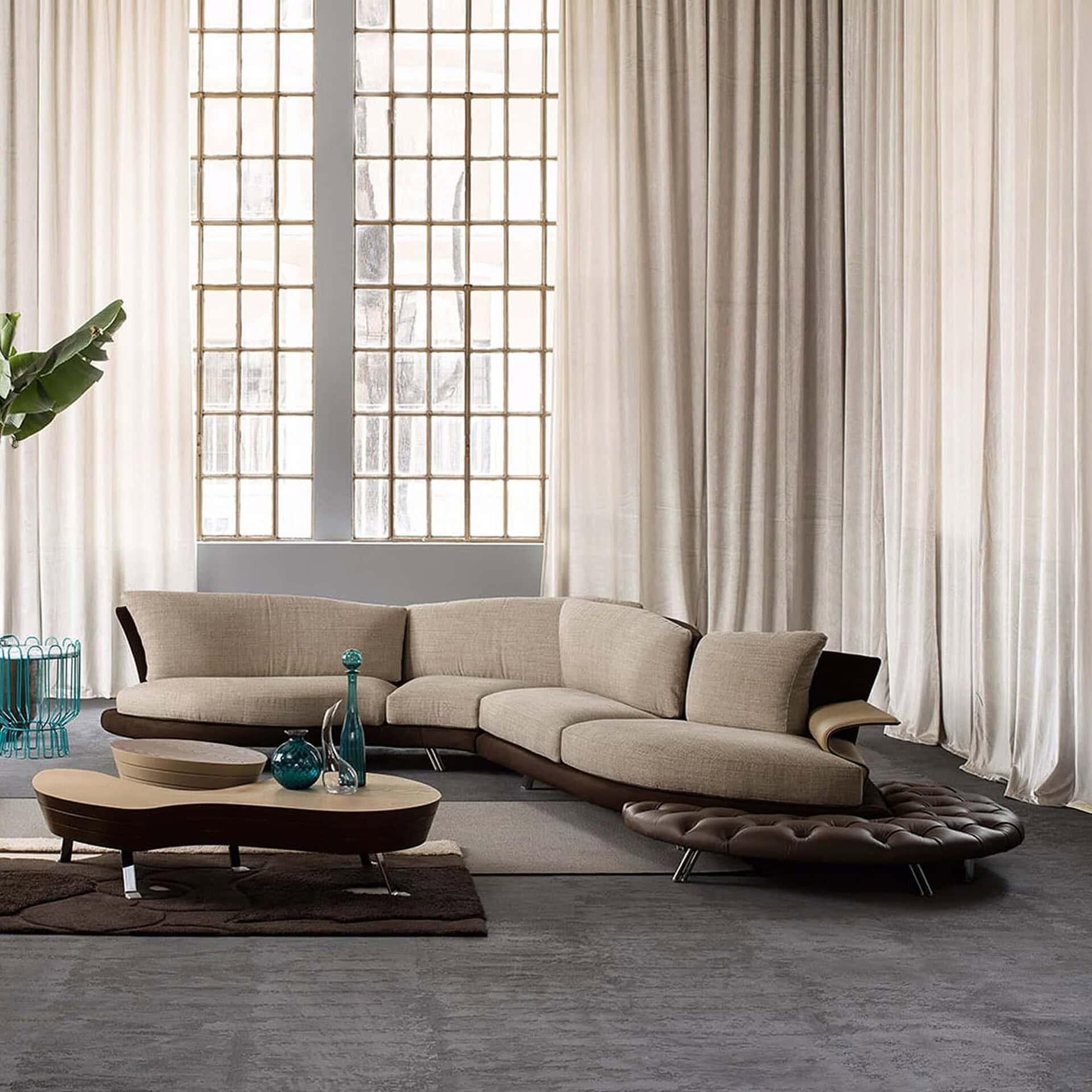 Contemporary living room with a beige Super Roy sofa styled with a round wooden coffee table and large windows.
