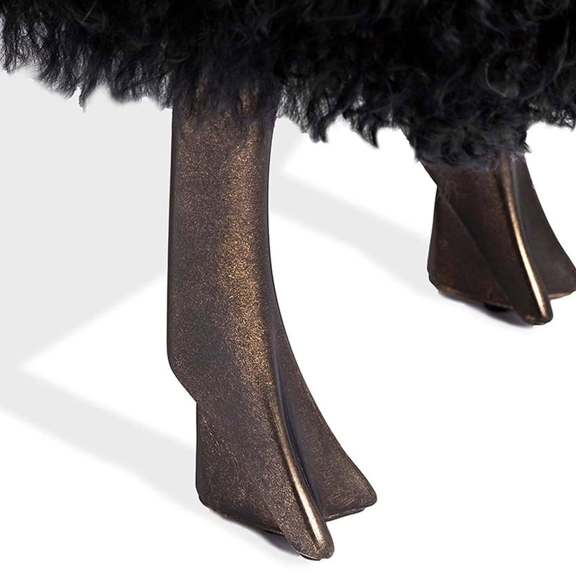 Close-up of antique bronze legs on the Leon Sheep Statue upholstered in black sheepskin.
