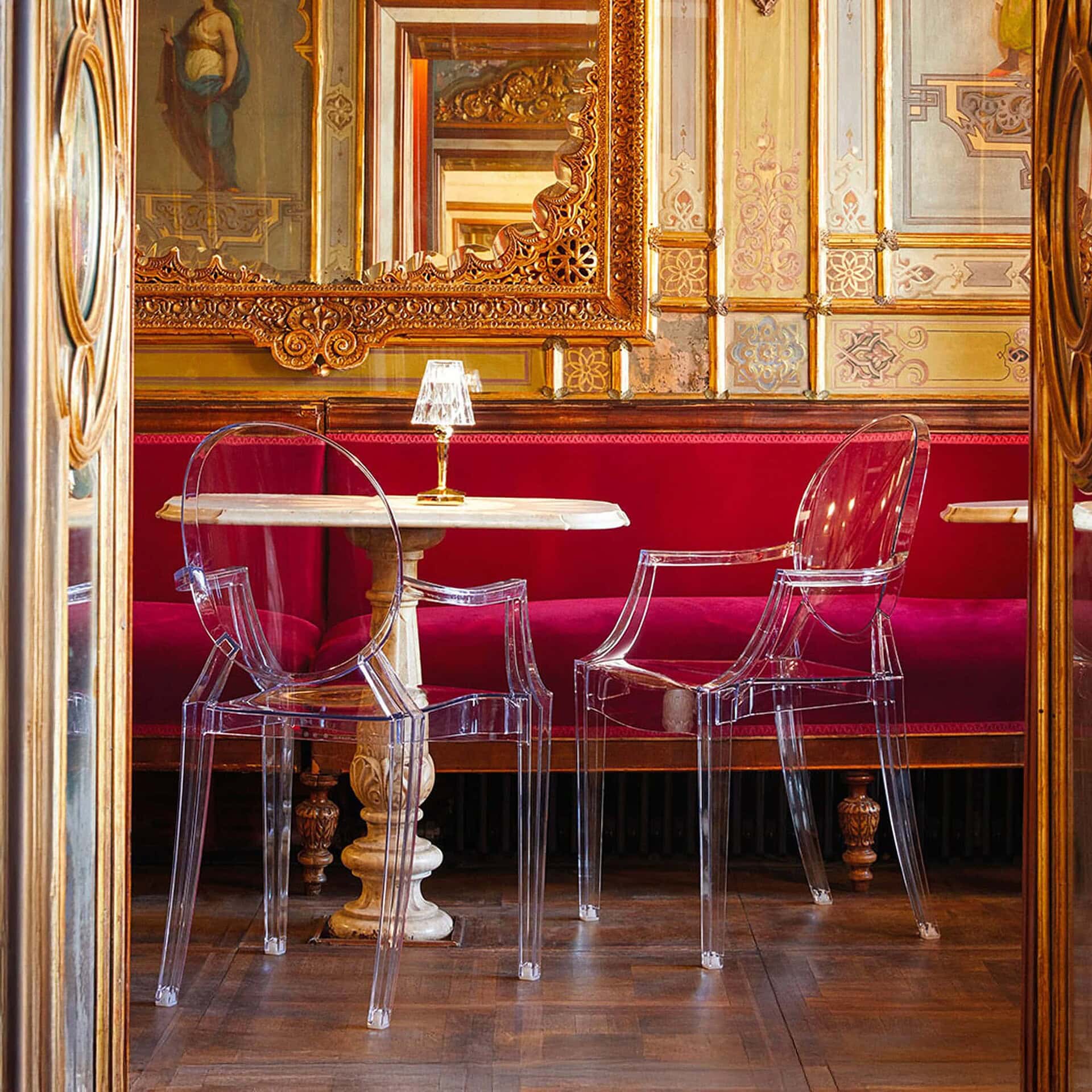 Louis Ghost Chairs in a café interior with red upholstered banquettes