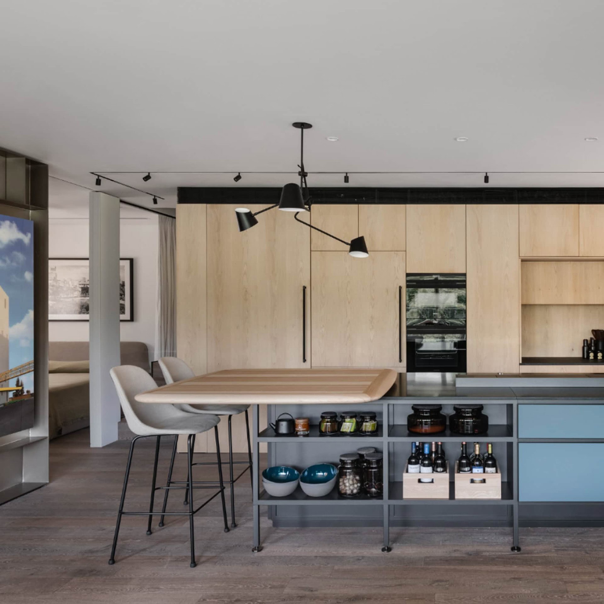 Sleek modern kitchen with wooden cabinets, black lighting fixtures, and stylish seating area.