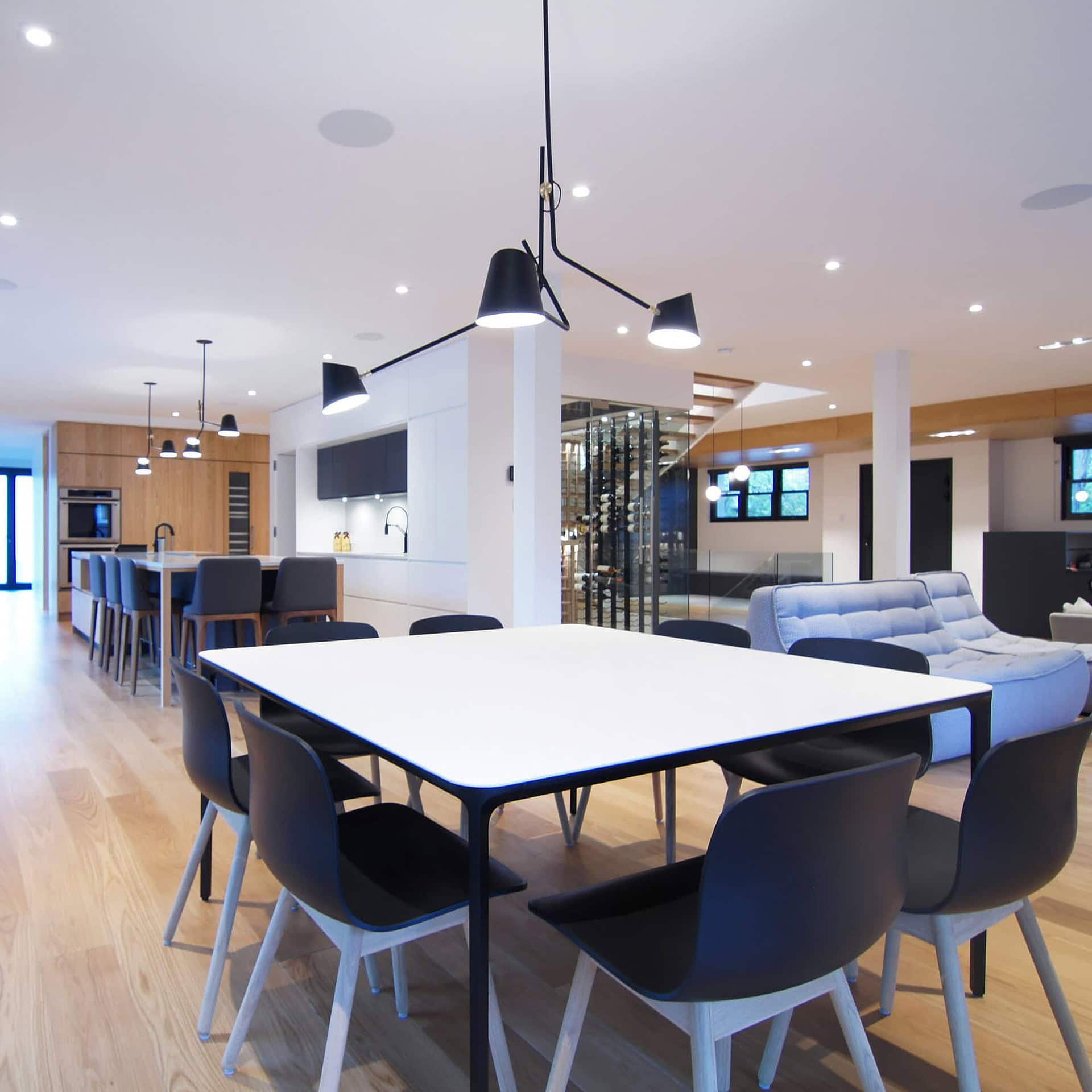 Contemporary dining area with modern black and white furniture, stylish pendant lighting, and open floor plan.