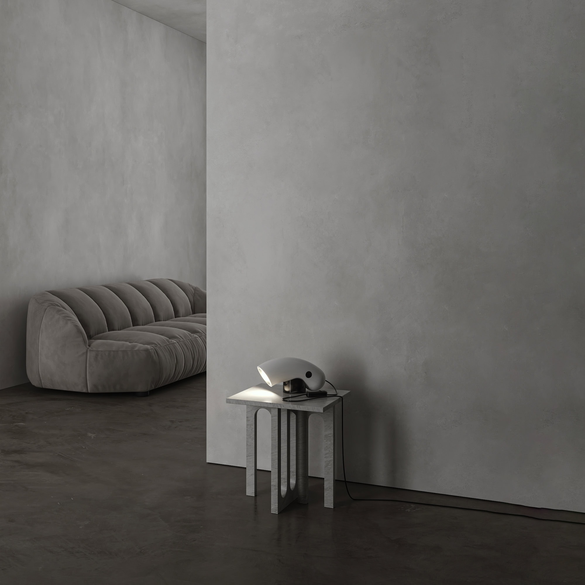 Soft gray velvet sofa in a minimalist modern living space with concrete flooring.