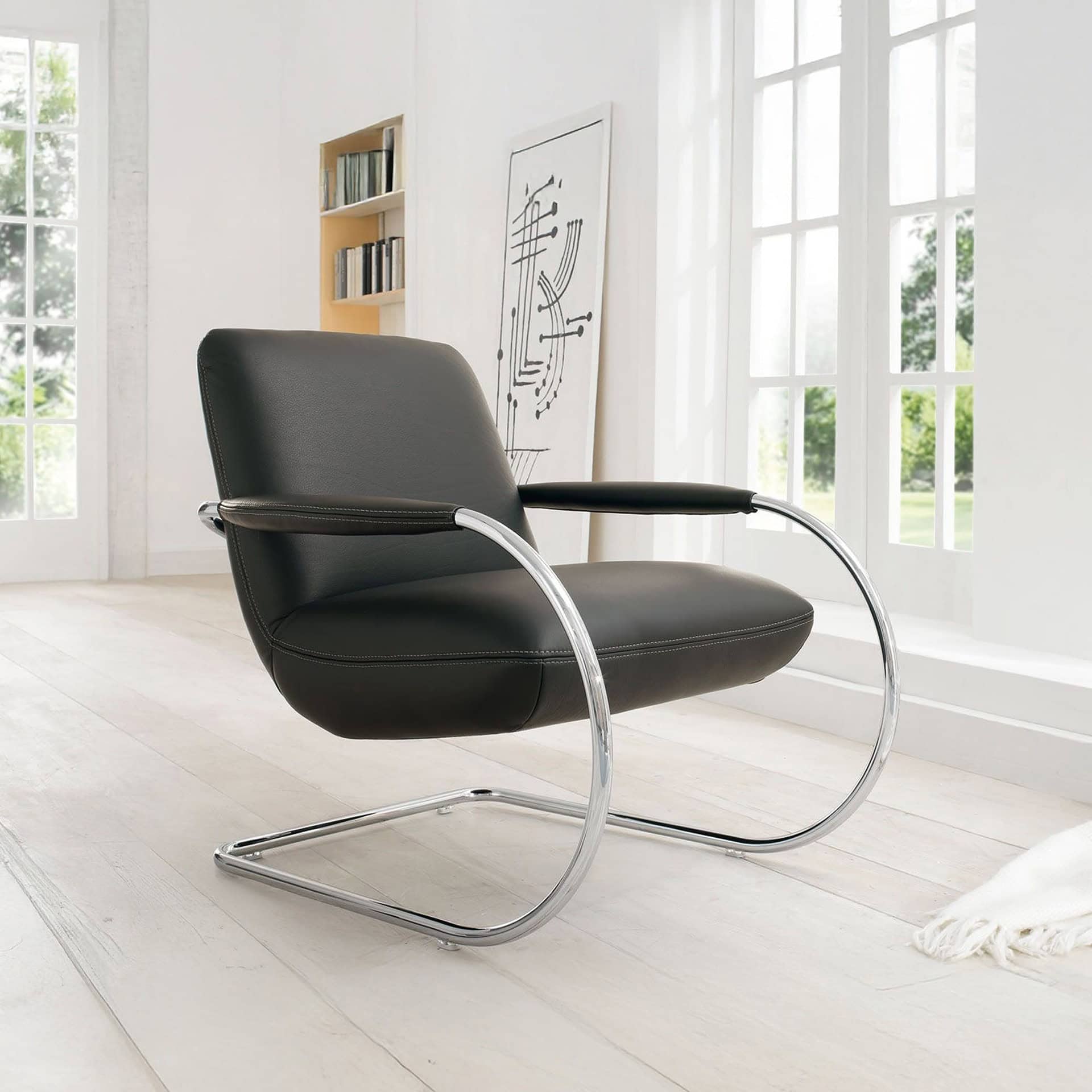 Jumper Cantilever Armchair in black leather with chrome base in a bright living space.