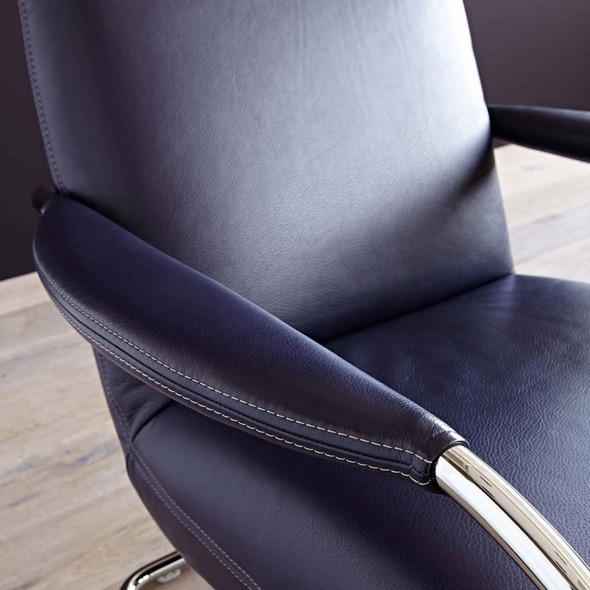 Detail of Jumper Cantilever Armchair armrest in navy leather upholstery.