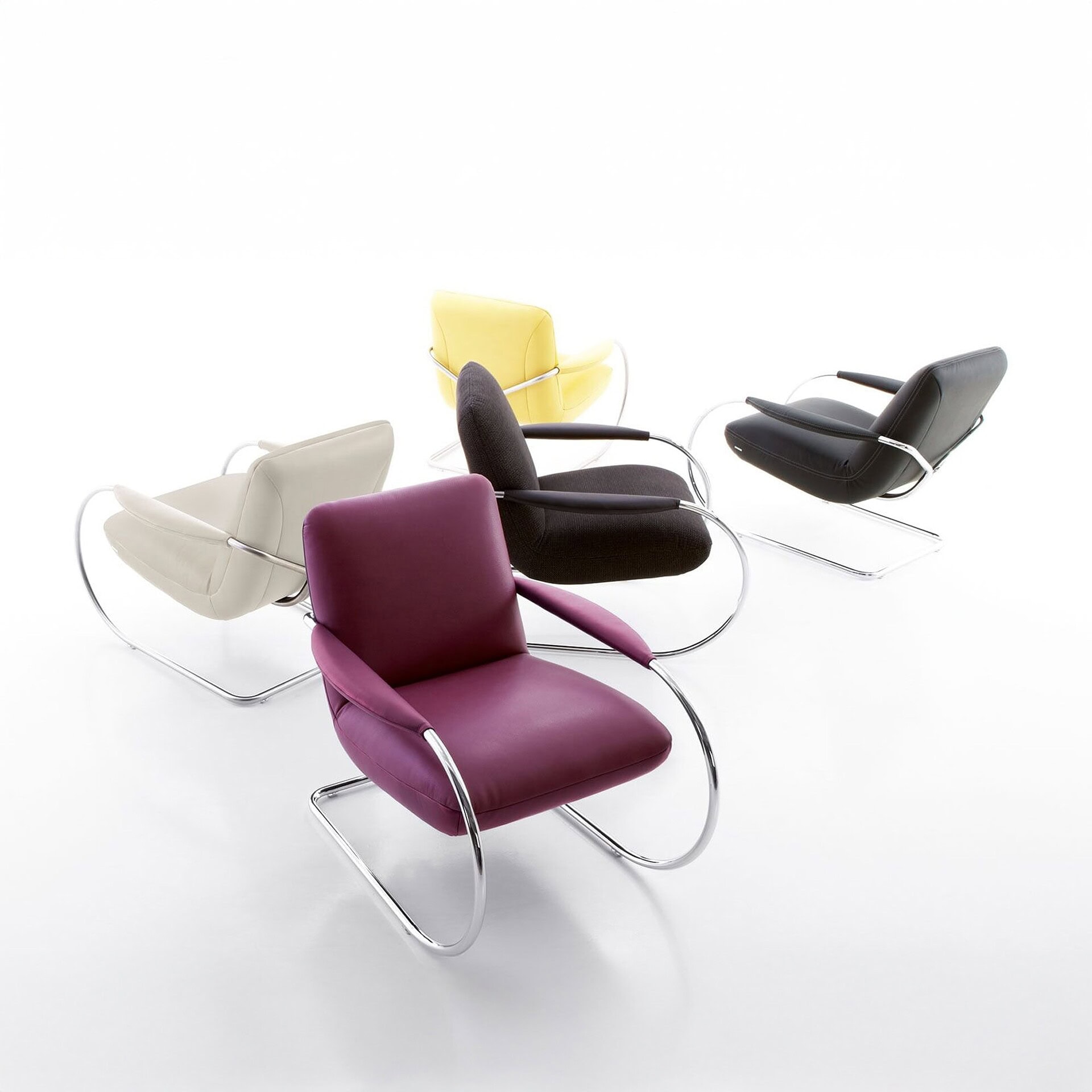 Studio shot of Jumper Cantilever Armchairs in purple, yellow, and black with matching stool.