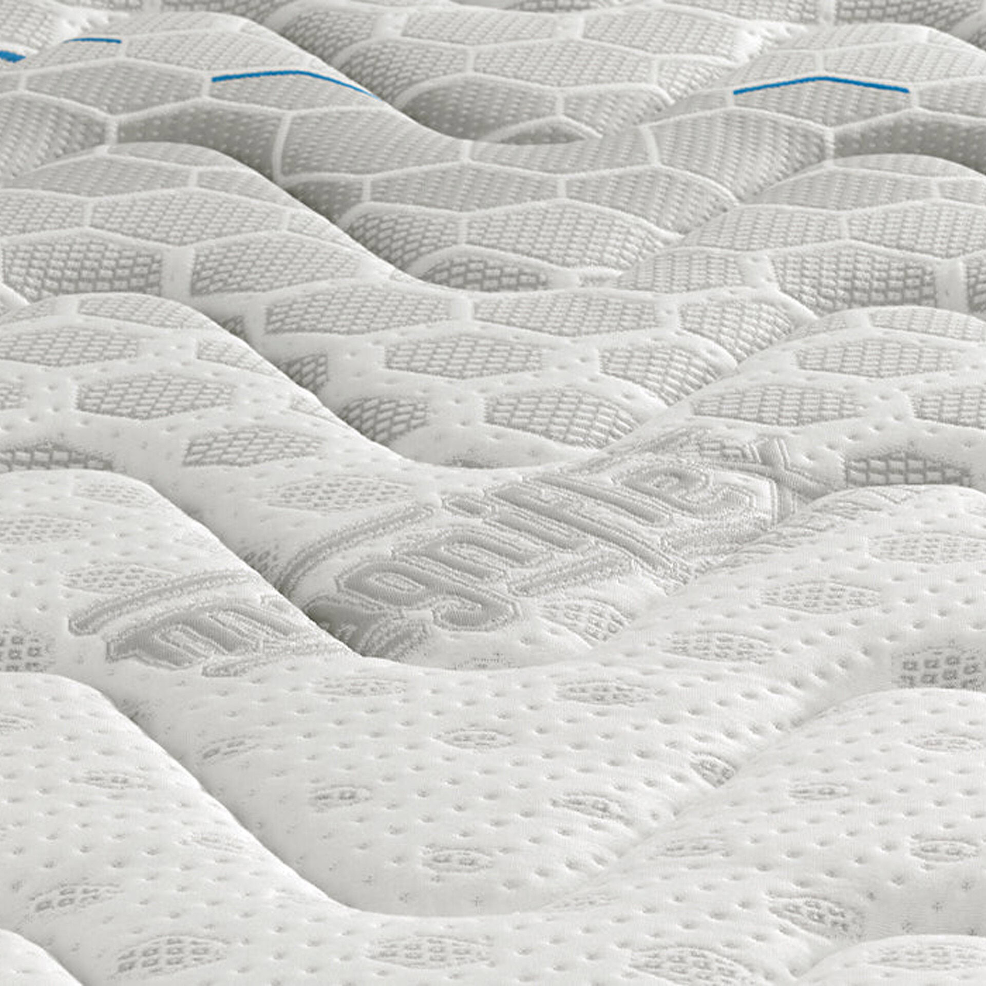 Close-up of a white mattress surface with light gray hexagonal quilting. The 'Magniflex' logo is embossed in gray, and two thin blue lines are visible in the upper portion.
