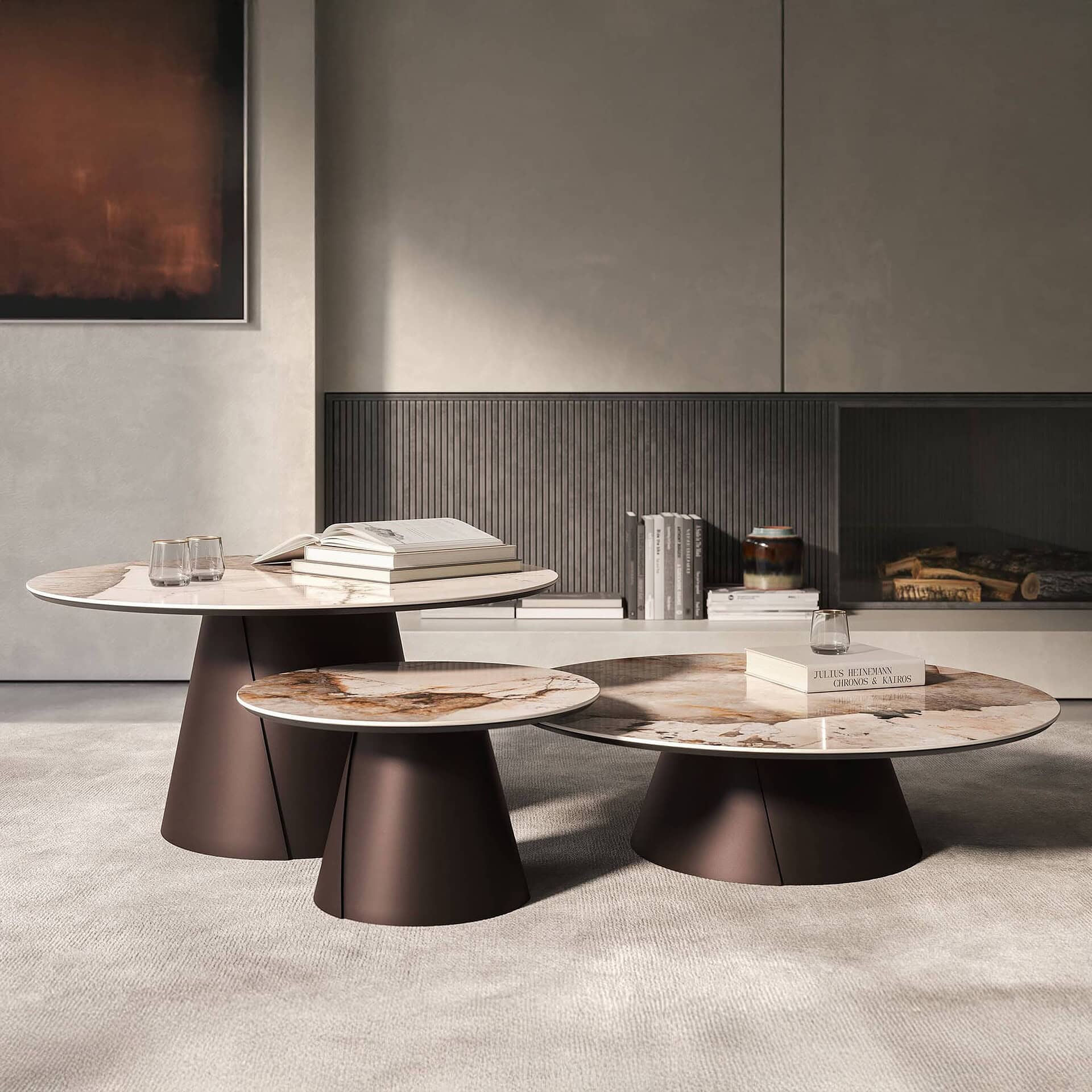 Three modern, round coffee tables with marble tops and dark bases in a stylish living room. The tables are adorned with books and glasses, set against a minimalist wall unit and an abstract painting.