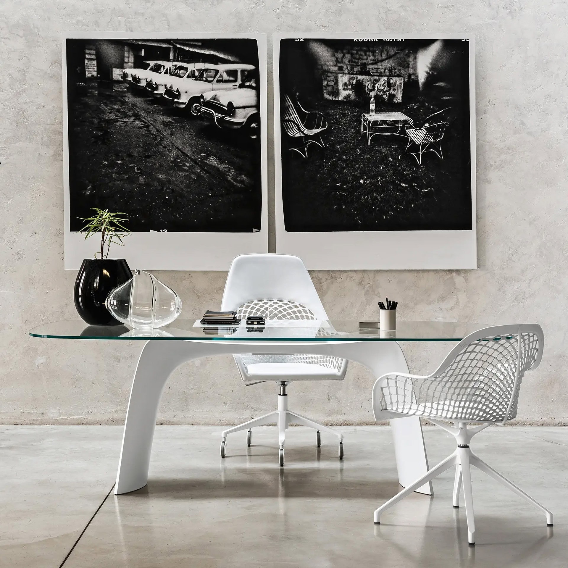 Modern office desk with sleek glass surface and stylish chairs.