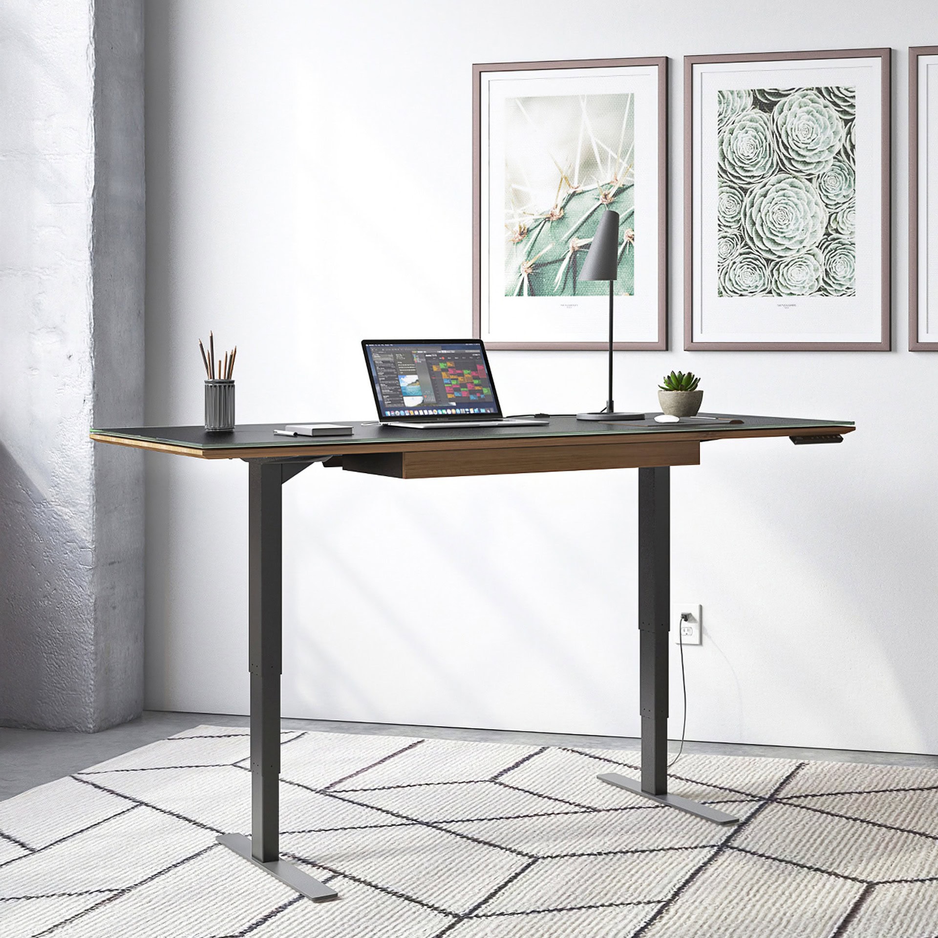 Sequel 20 6152 Sit-Stand Desk raised to standing height with natural light and laptop setup.