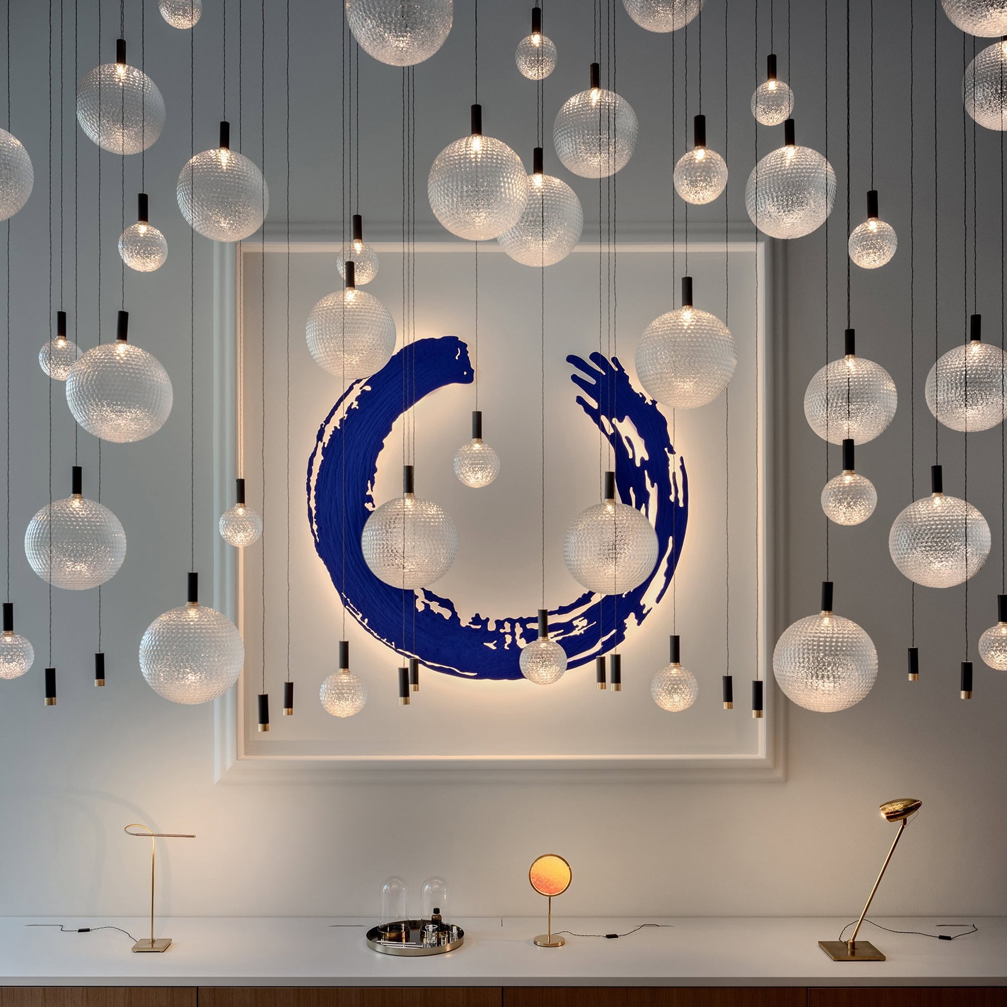 Suspended modern glass orb pendant lights with black accents, artistic blue wall decor, contemporary interior design.