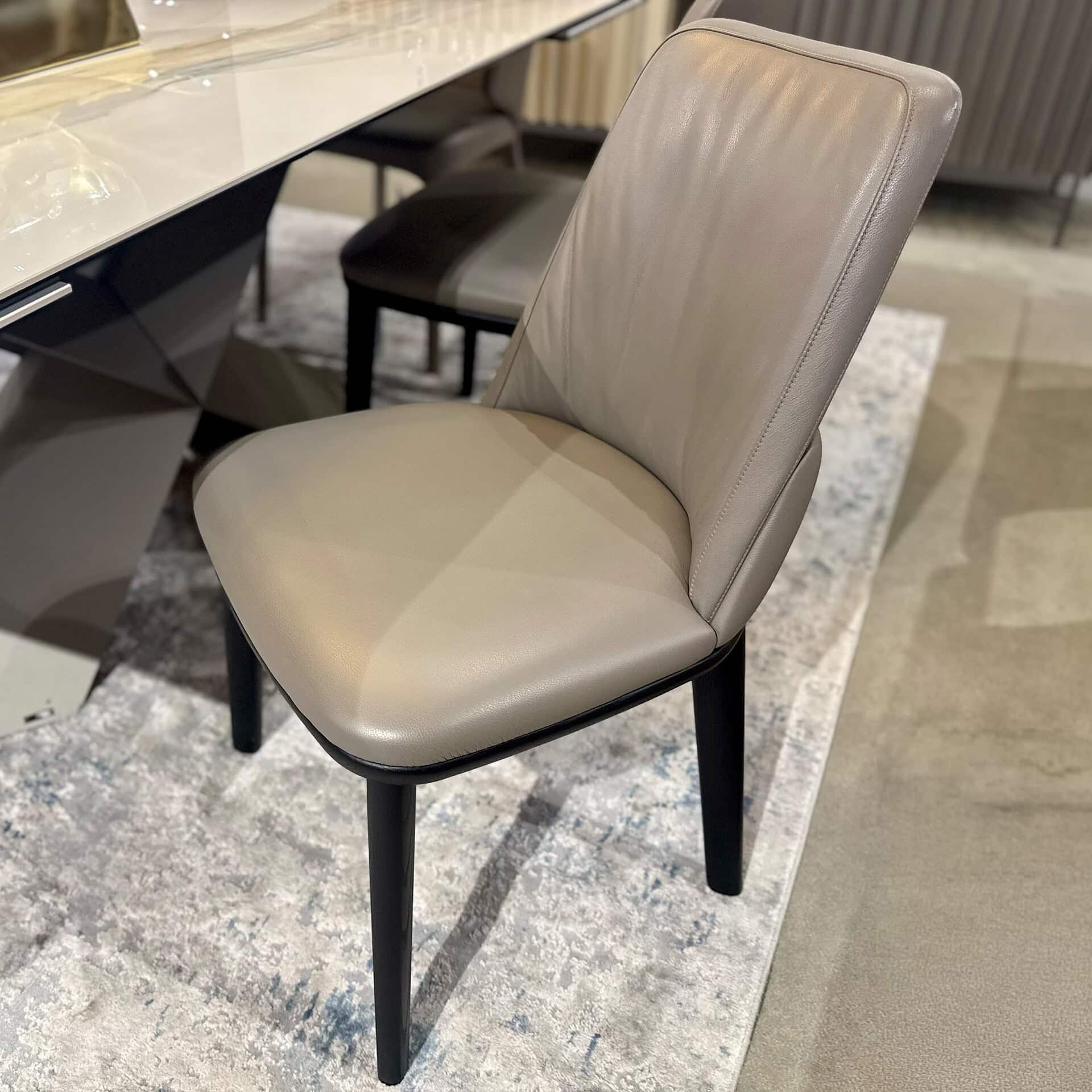 Upholstered dining chair with sleek design and neutral fabric, perfect for modern dining rooms.