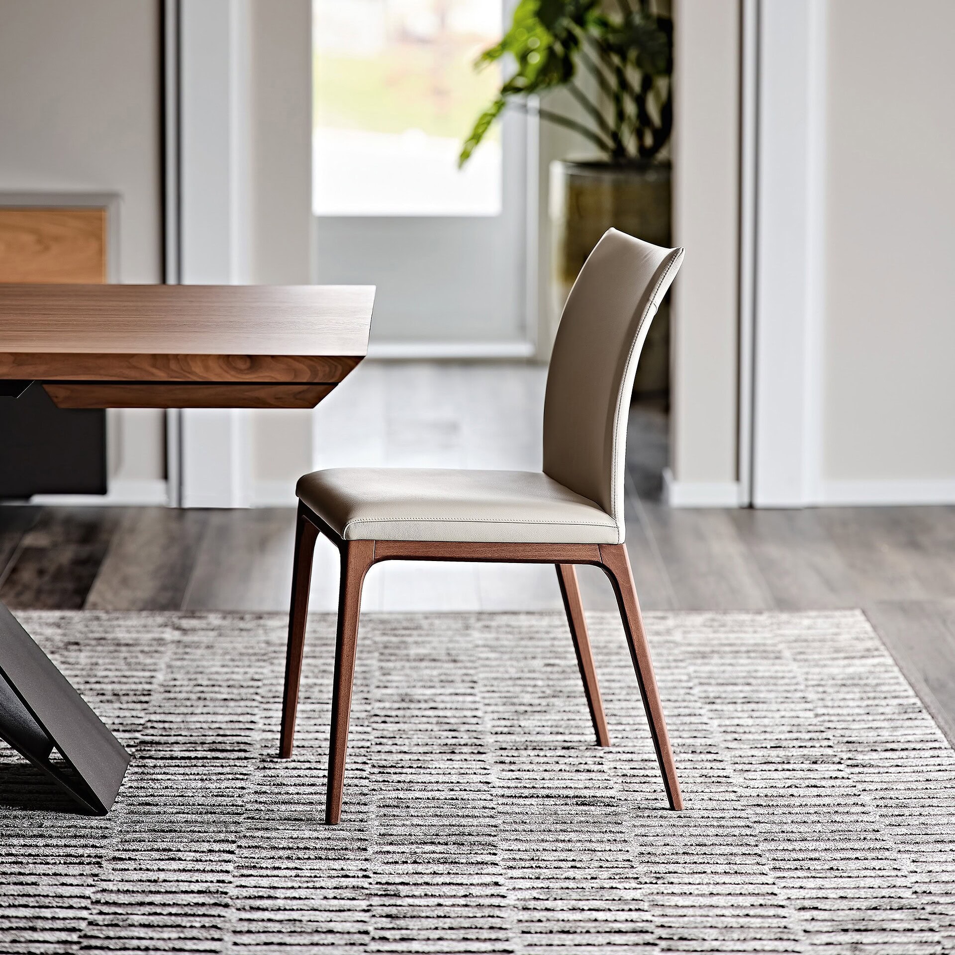 Arcadia Low Back Dining Chair in soft leather Cenere with Canaletto walnut legs, front angled view in modern dining room