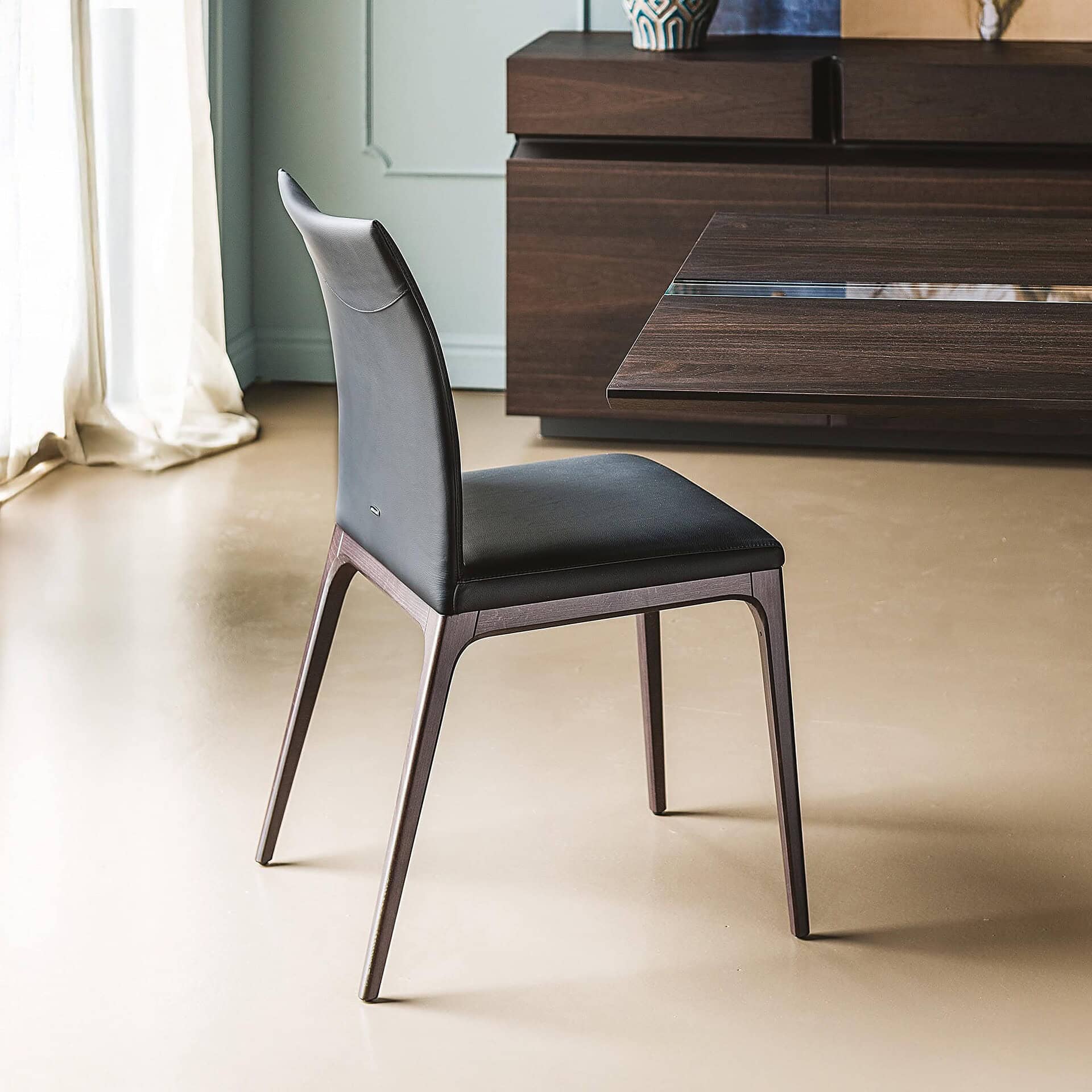 Sleek modern dining chair with dark wood finish and black leather upholstery for contemporary home decor.