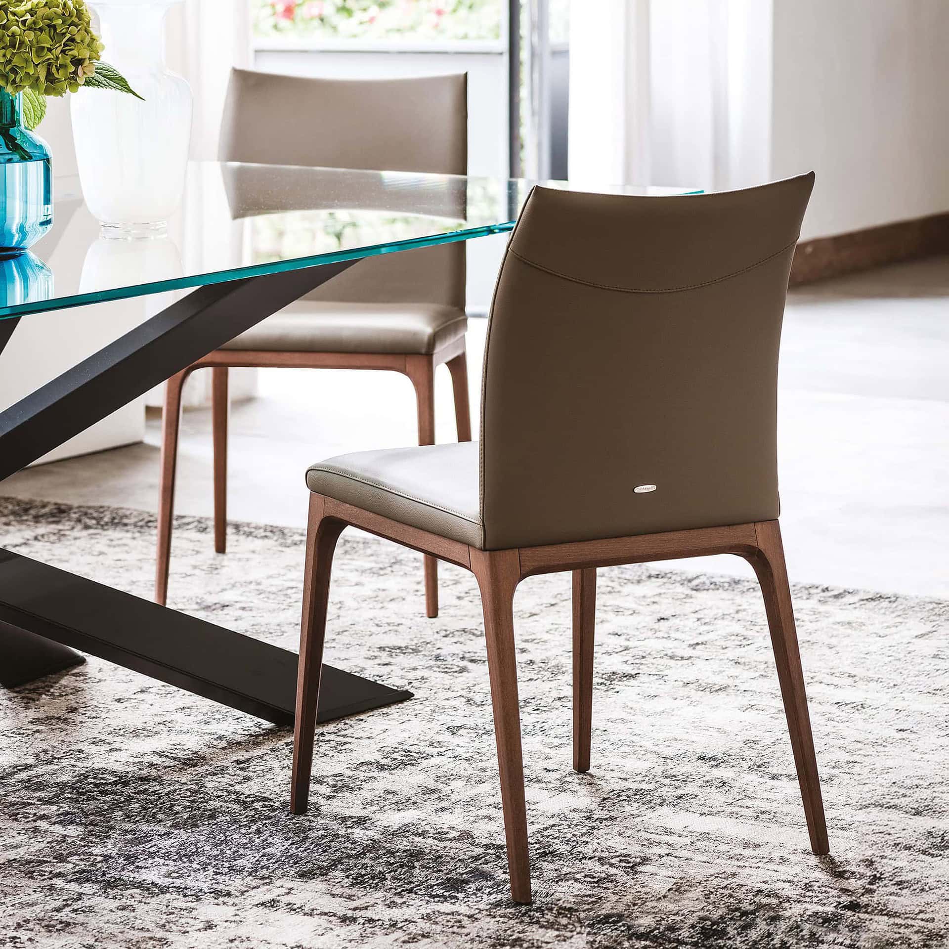 Contemporary dining chairs with upholstered seats and wooden legs in a modern dining room setting.