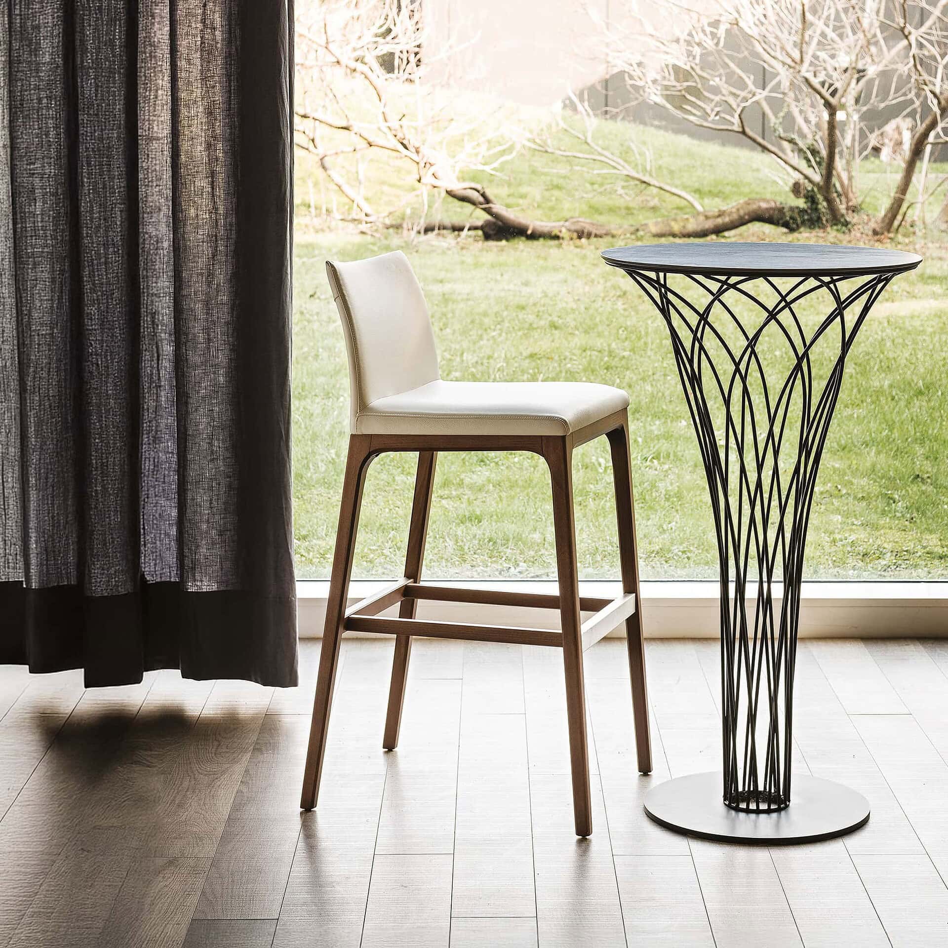 Modern white upholstered barstool with wooden legs near sliding glass door.
