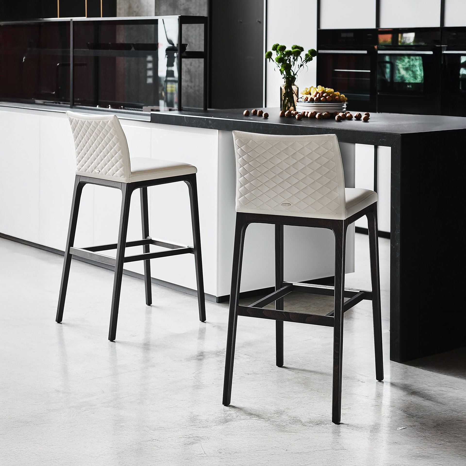 Modern dining chairs with quilted white upholstery and black wooden legs.