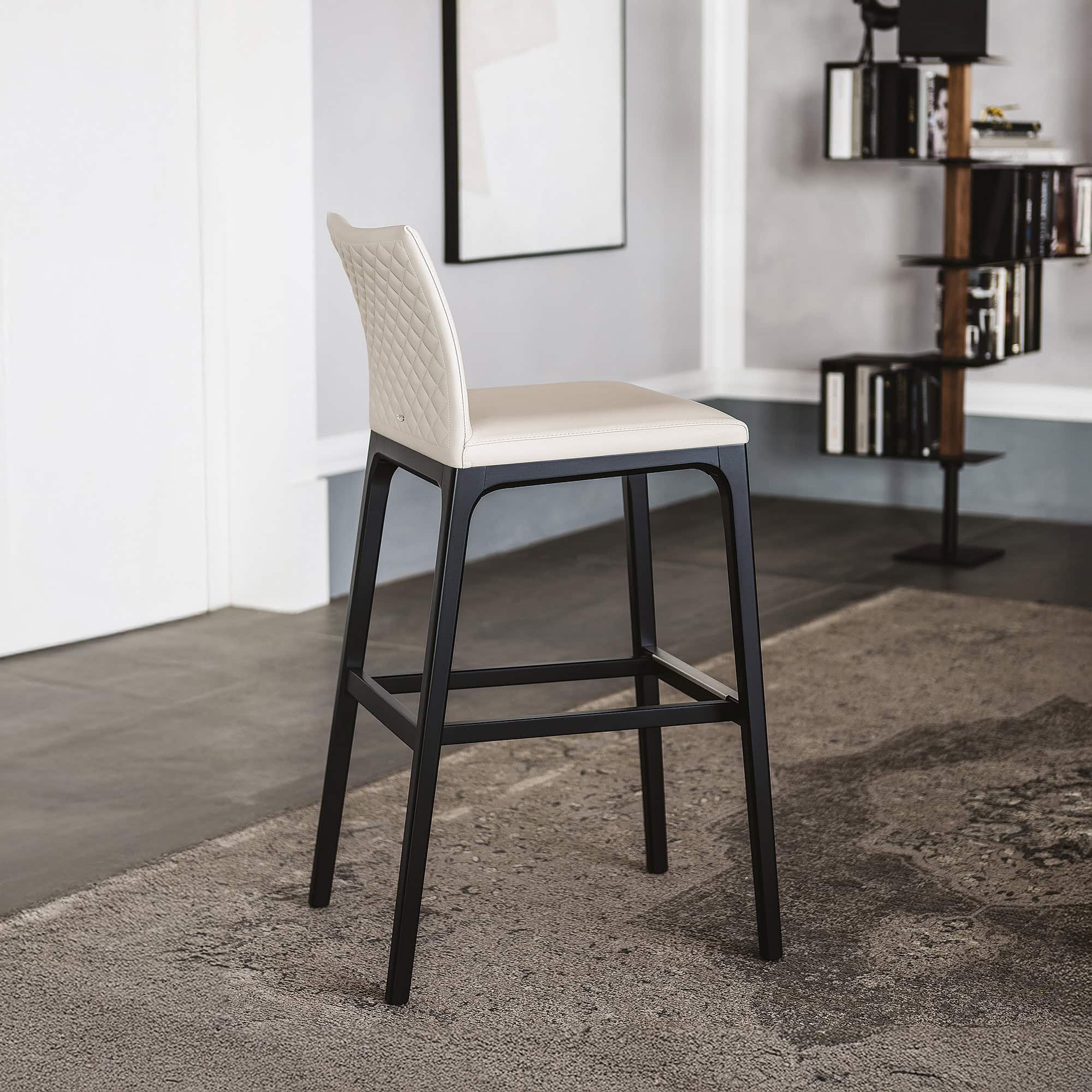 Black and white barstool with quilted leather backrest in modern interior dining space.