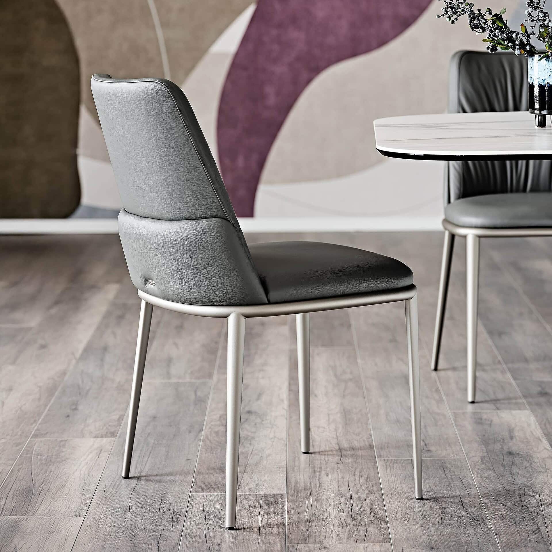 Modern grey upholstered dining chair with sleek metal legs and contemporary design.