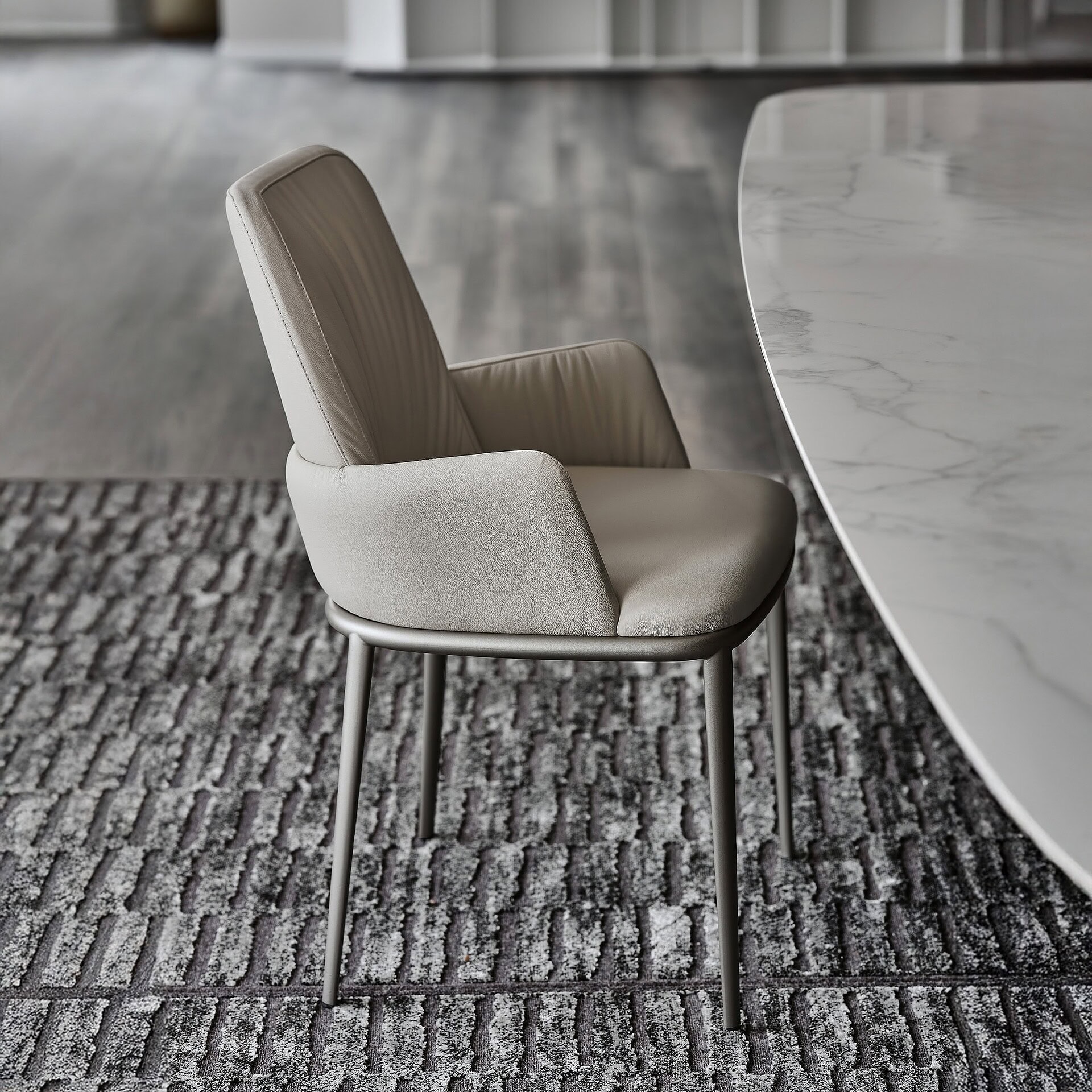Armchair with beige upholstery and sleek metal legs in modern dining space.