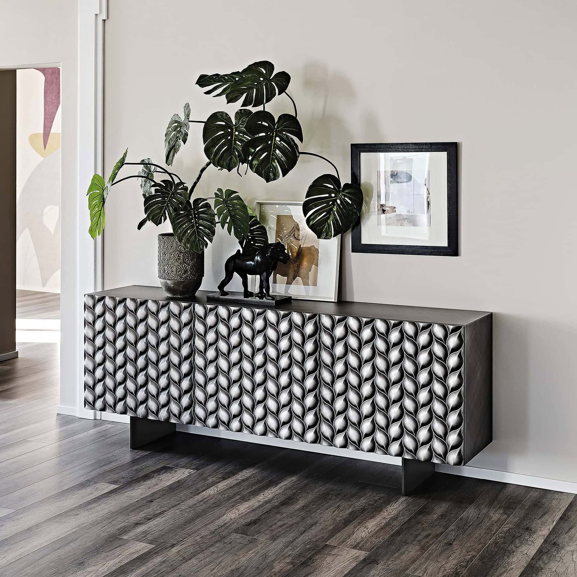 Contemporary black and white patterned sideboard with decor, plants, and wall art in modern living space.