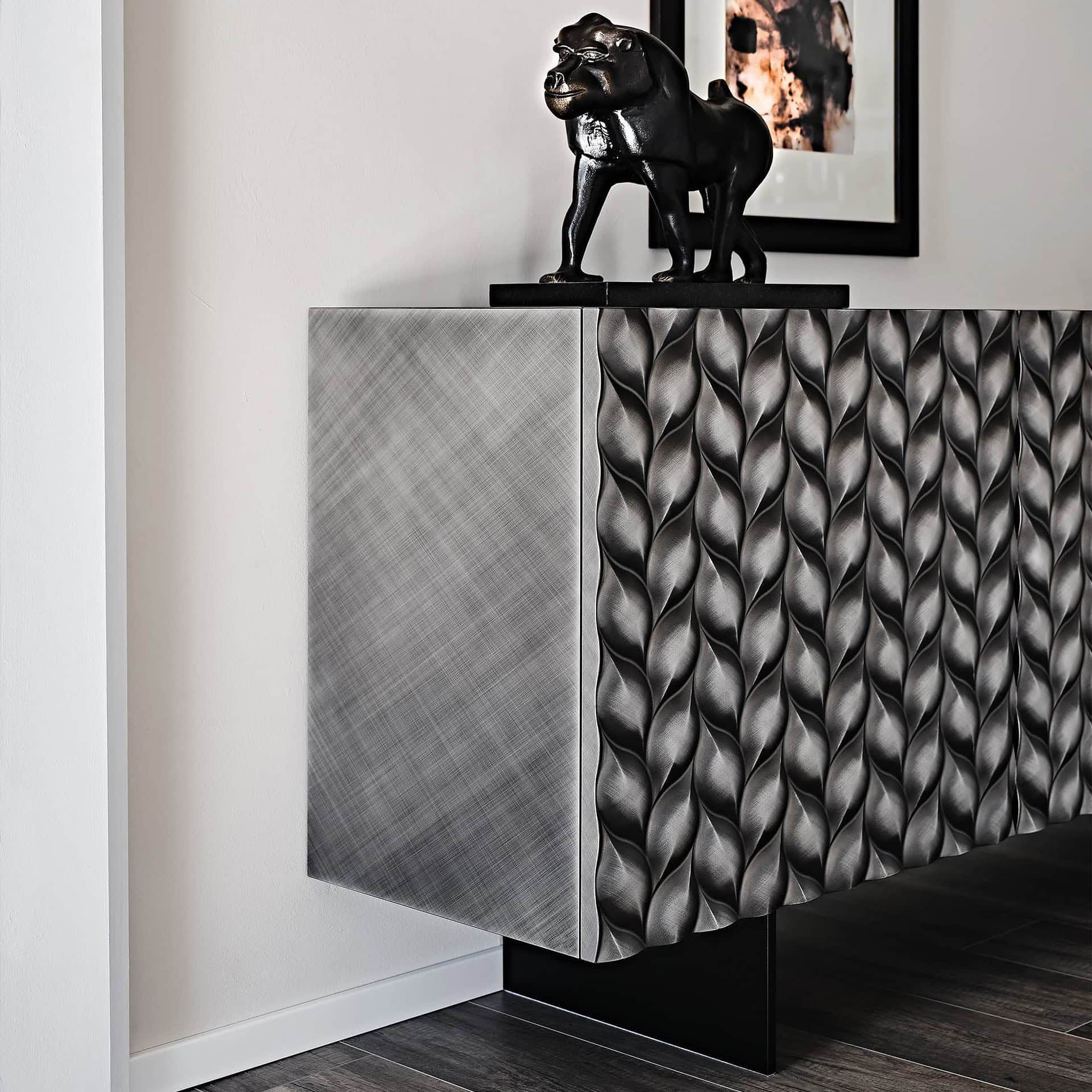 Contemporary textured silver sideboard with sculptural black decorative sculpture on top.