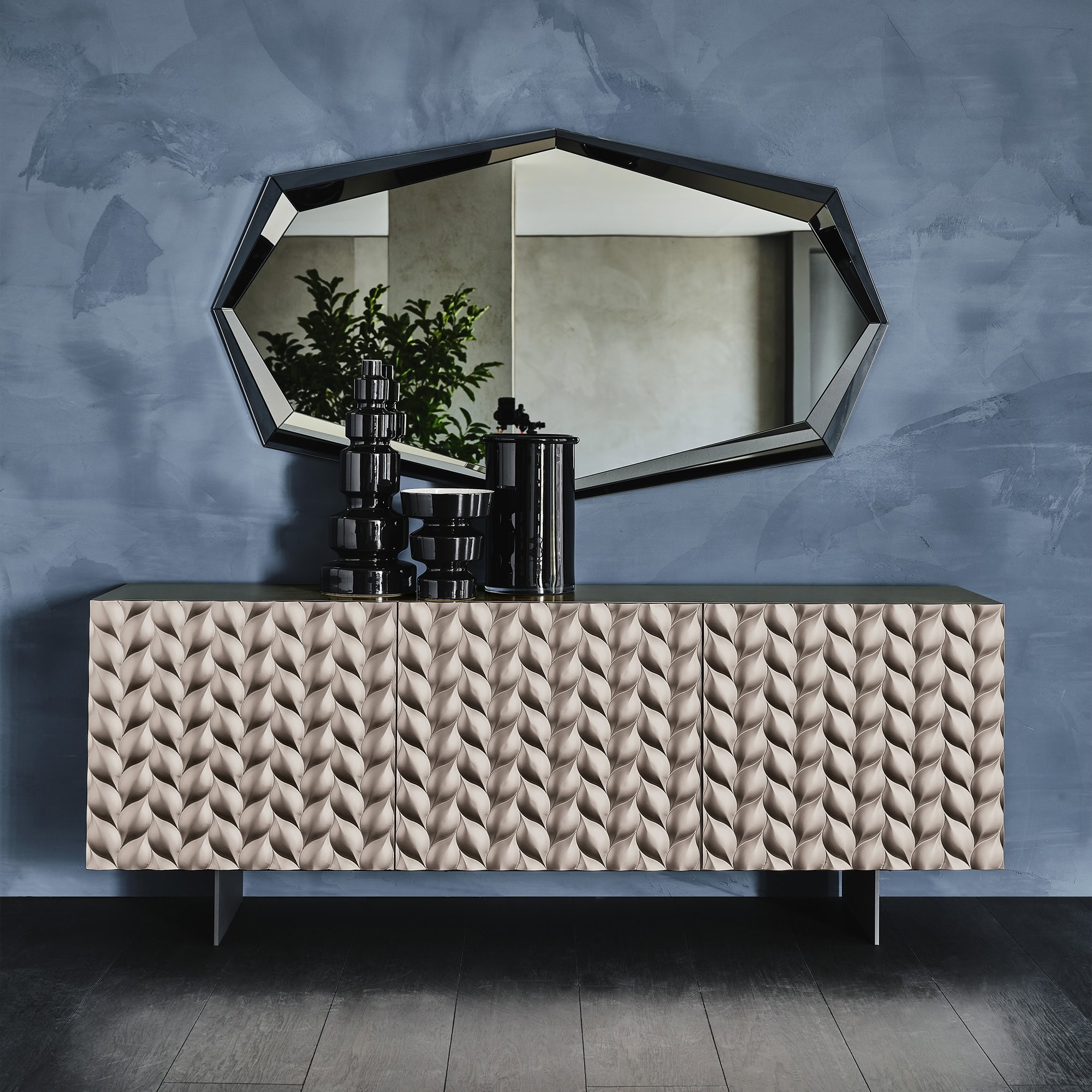 Luxurious modern sideboard with textured geometric design in soft beige, accompanying black decorative accessories and large wall mirror, in contemporary home decor.