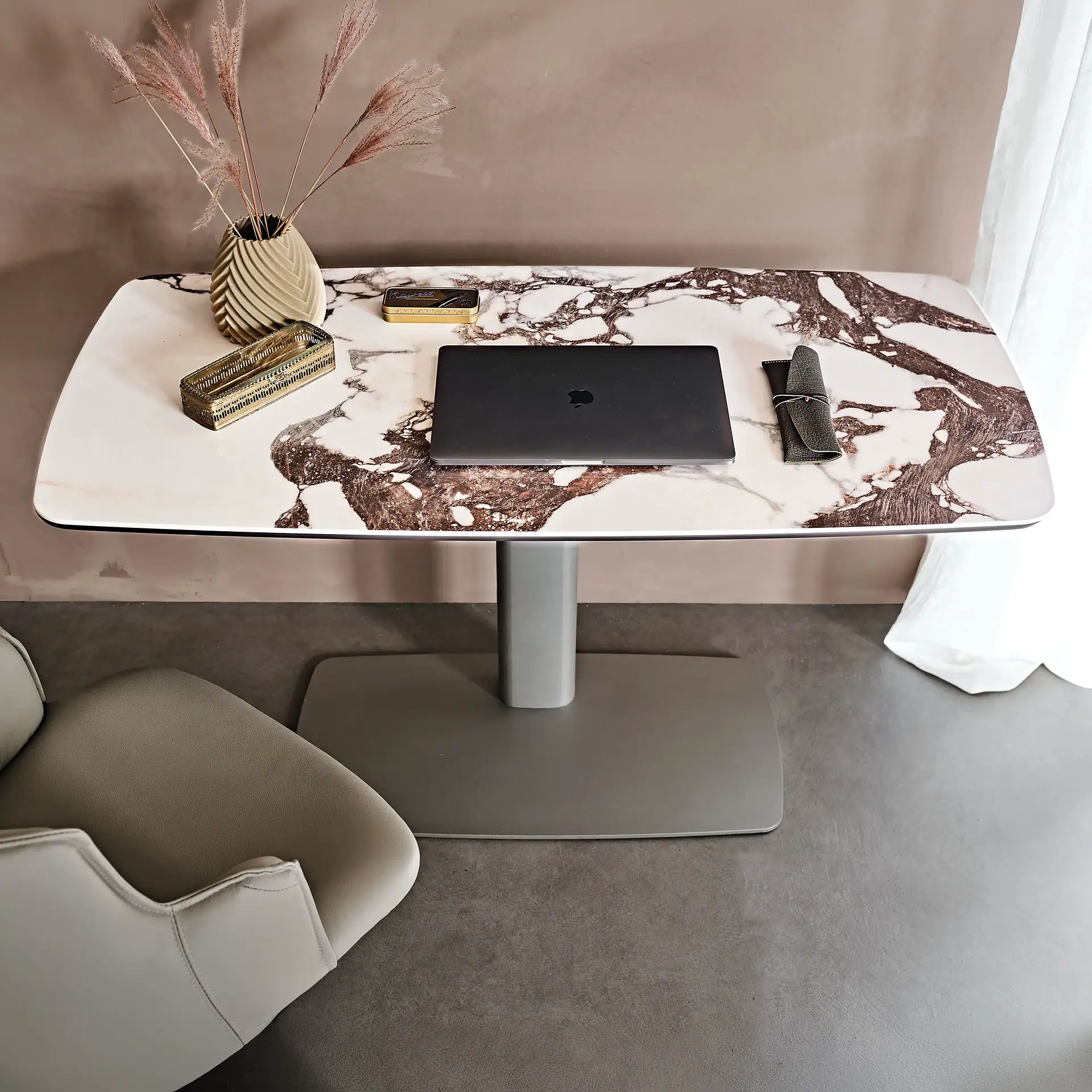 Marble top desk with laptop, vase, and decorative items in a modern room.