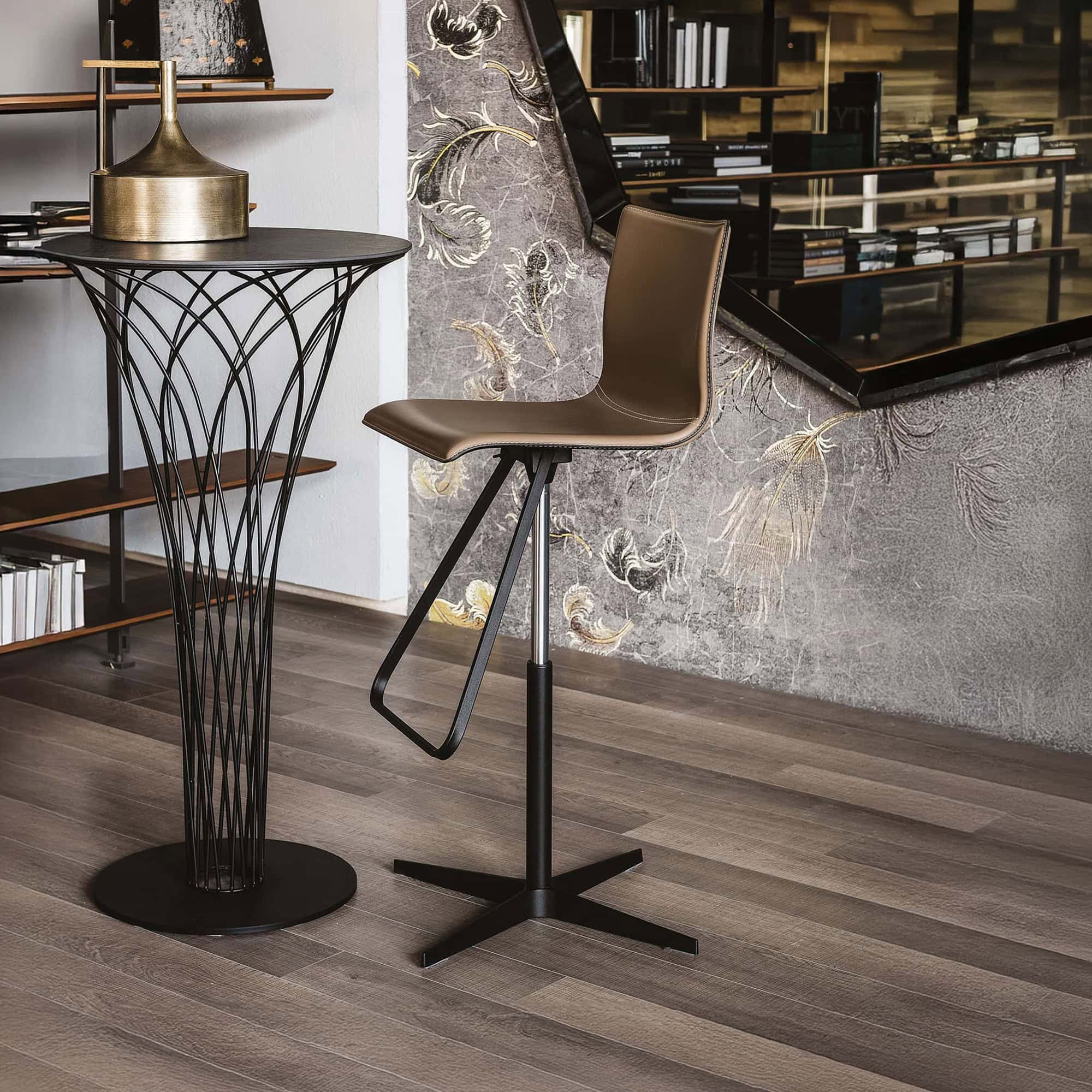 Contemporary bar stool with brown leather seat and black metal base, modern interior design.