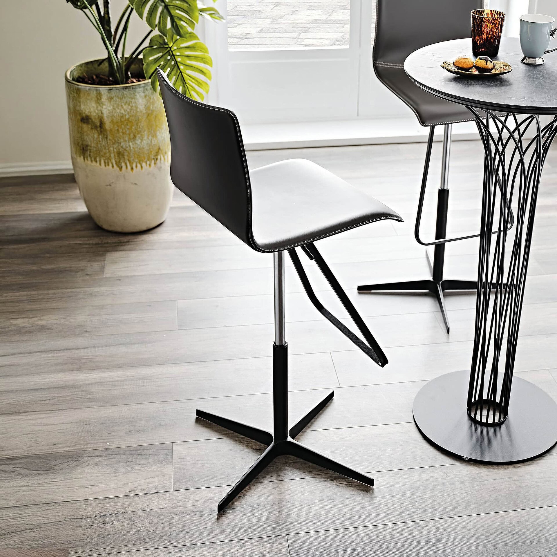 Modern Toto X stool in white leather with black base, styled beside a café table.