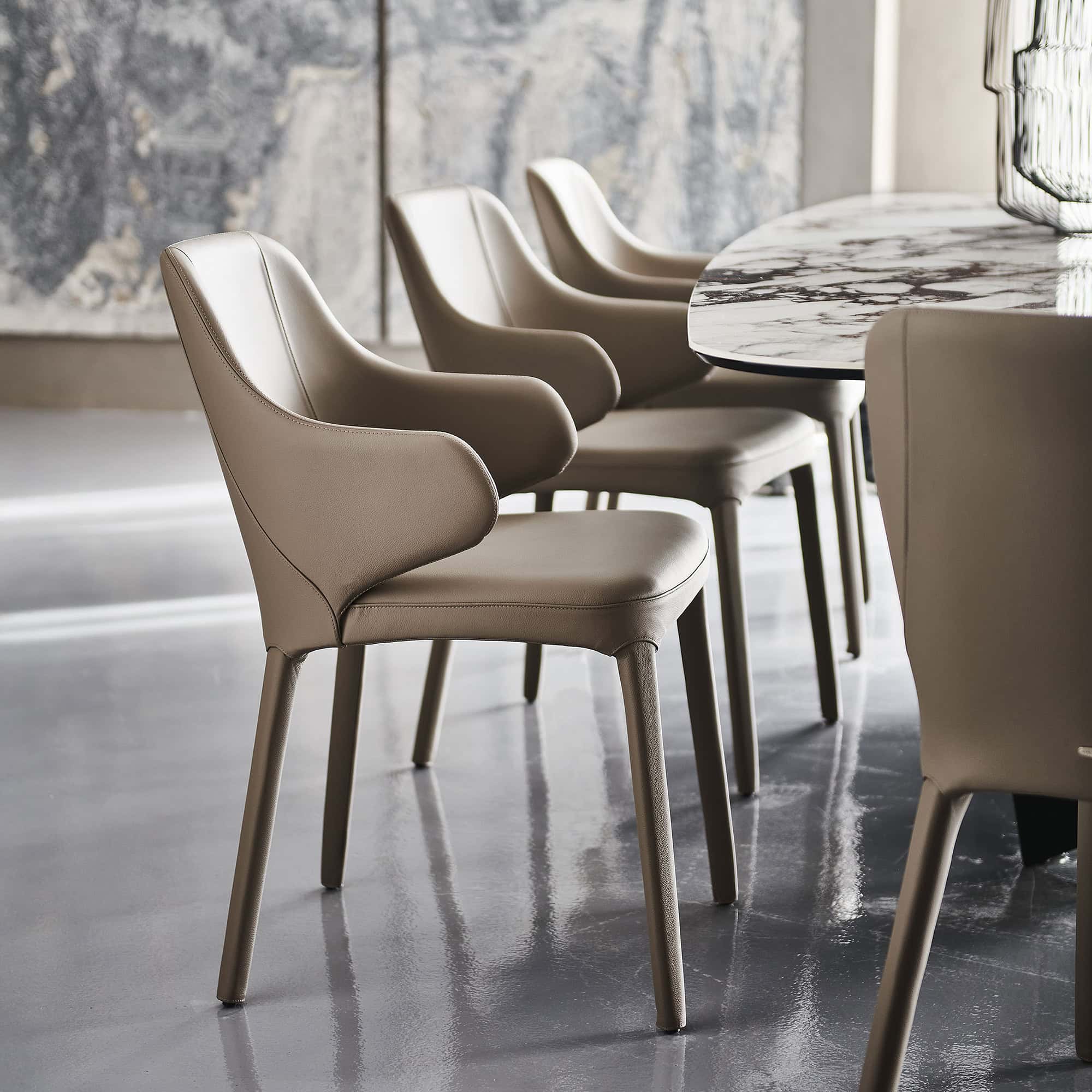 Luxurious beige leather dining chairs around a marble table in elegant restaurant setting.