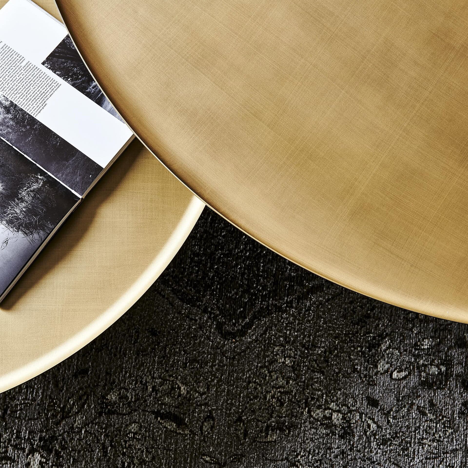 Detail shot of Amerigo Round Coffee Table showing the reflective bronze mirrored glass top with brushed steel base.