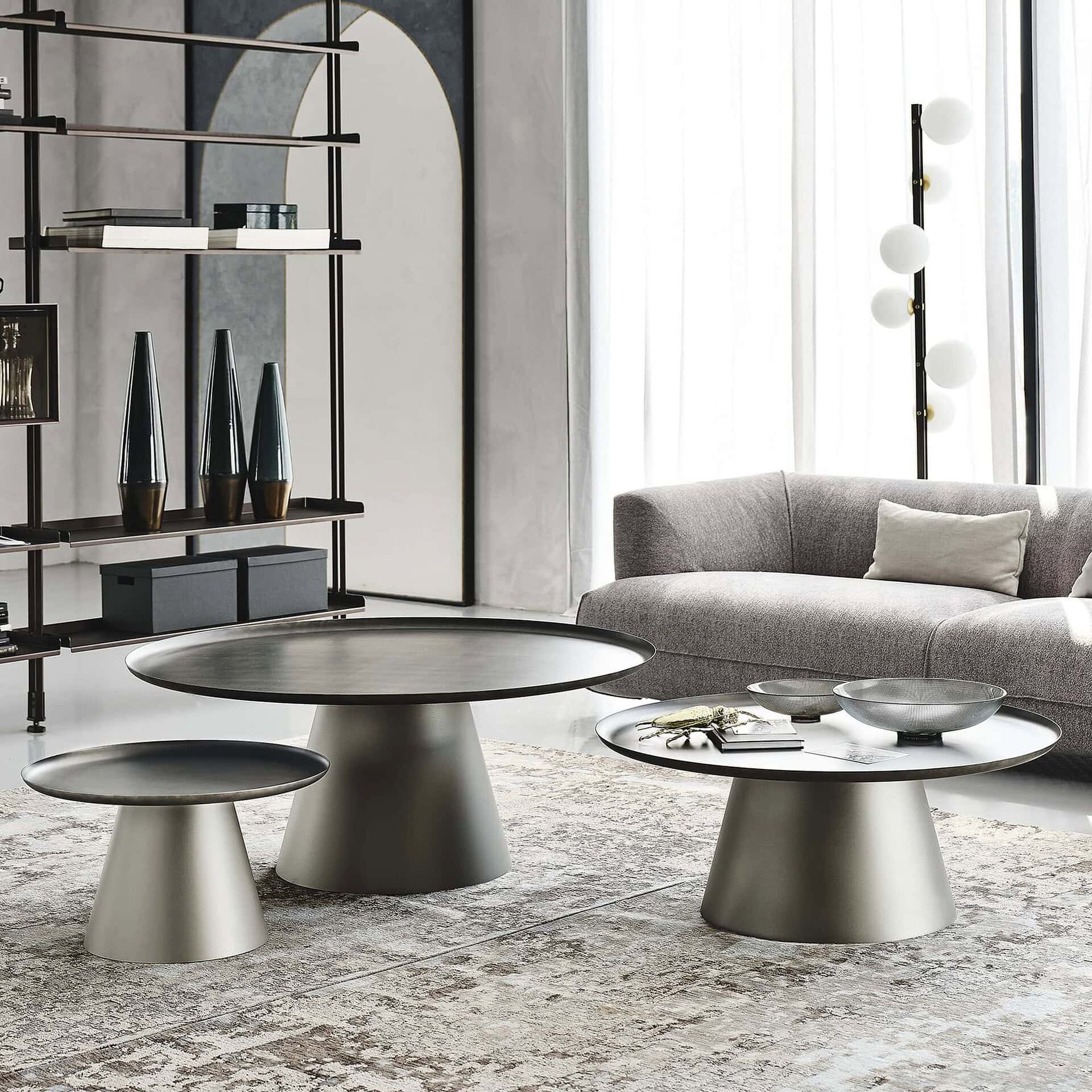 Amerigo Round Coffee Tables with bronze mirrored glass top and brushed base, positioned beside a contemporary sofa.