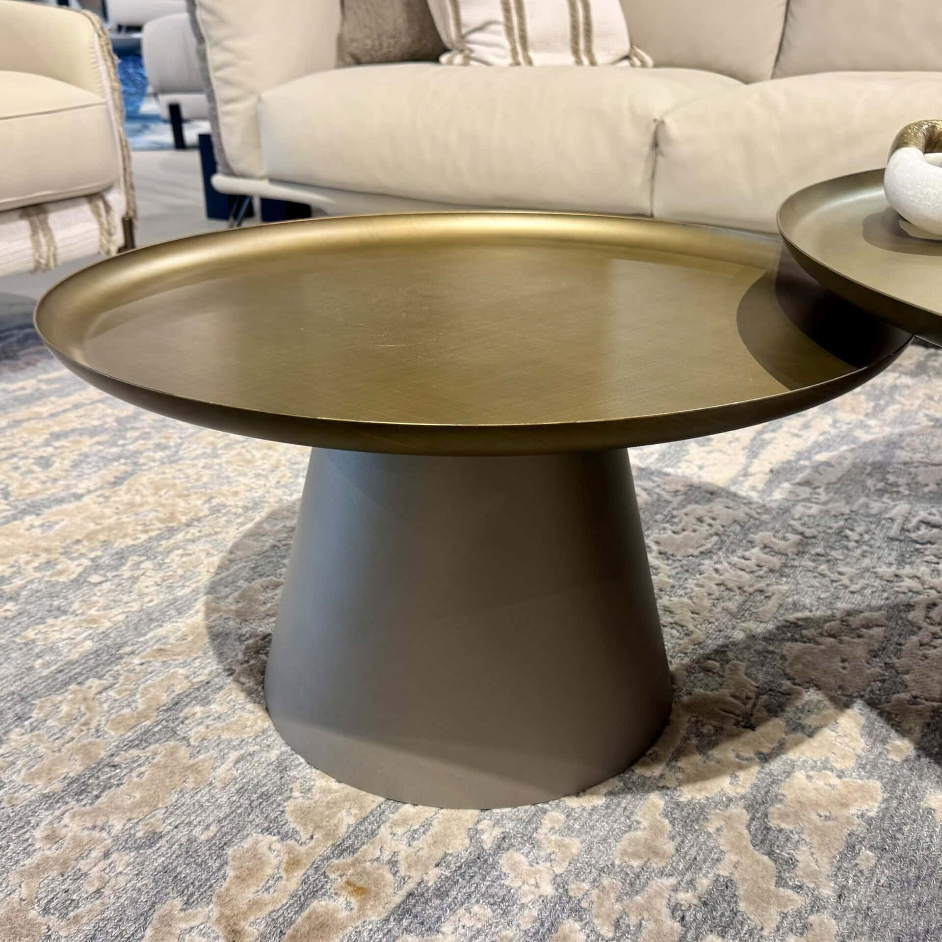 Amerigo round coffee table with a gold top and gray base.